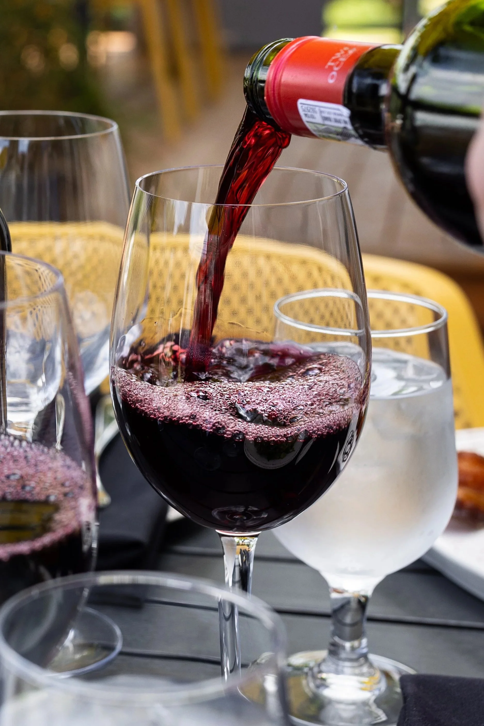 Red wine being poured into a glass at on a patio table at Maxwell's Steak & Seafood.