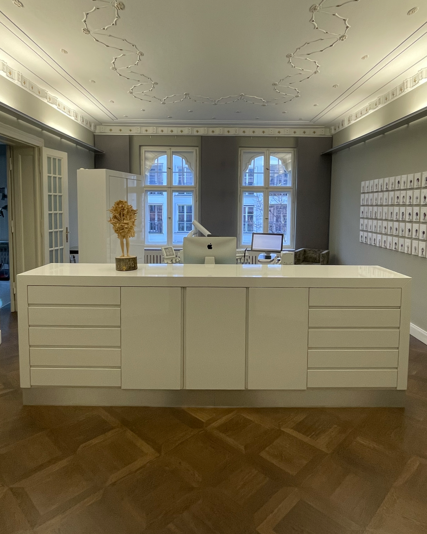 Weiße Rezeption in einem eleganten Raum mit großen Fenstern, Holzfußboden und Wanddekorationen.