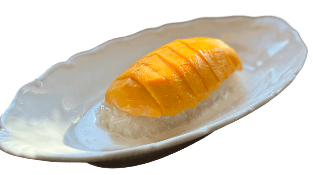 Mango with Coconut Sticky Rice — sliced fresh mango fanned over a mound of white sticky rice on an organic-shaped white plate.