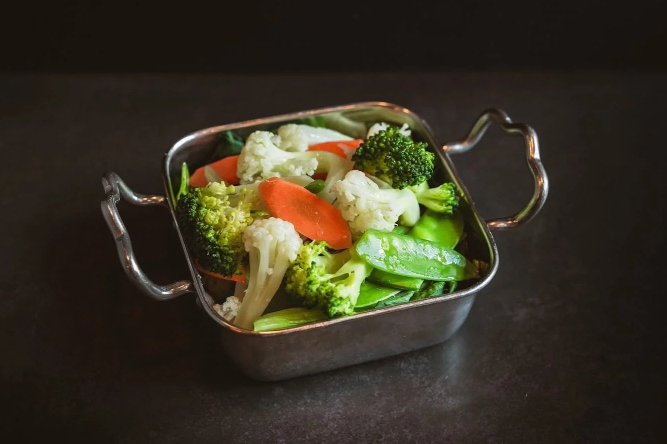 Steamed Mixed Vegetables with broccoli, cauliflower, carrot, and snow peas in a stainless steel serving dish.