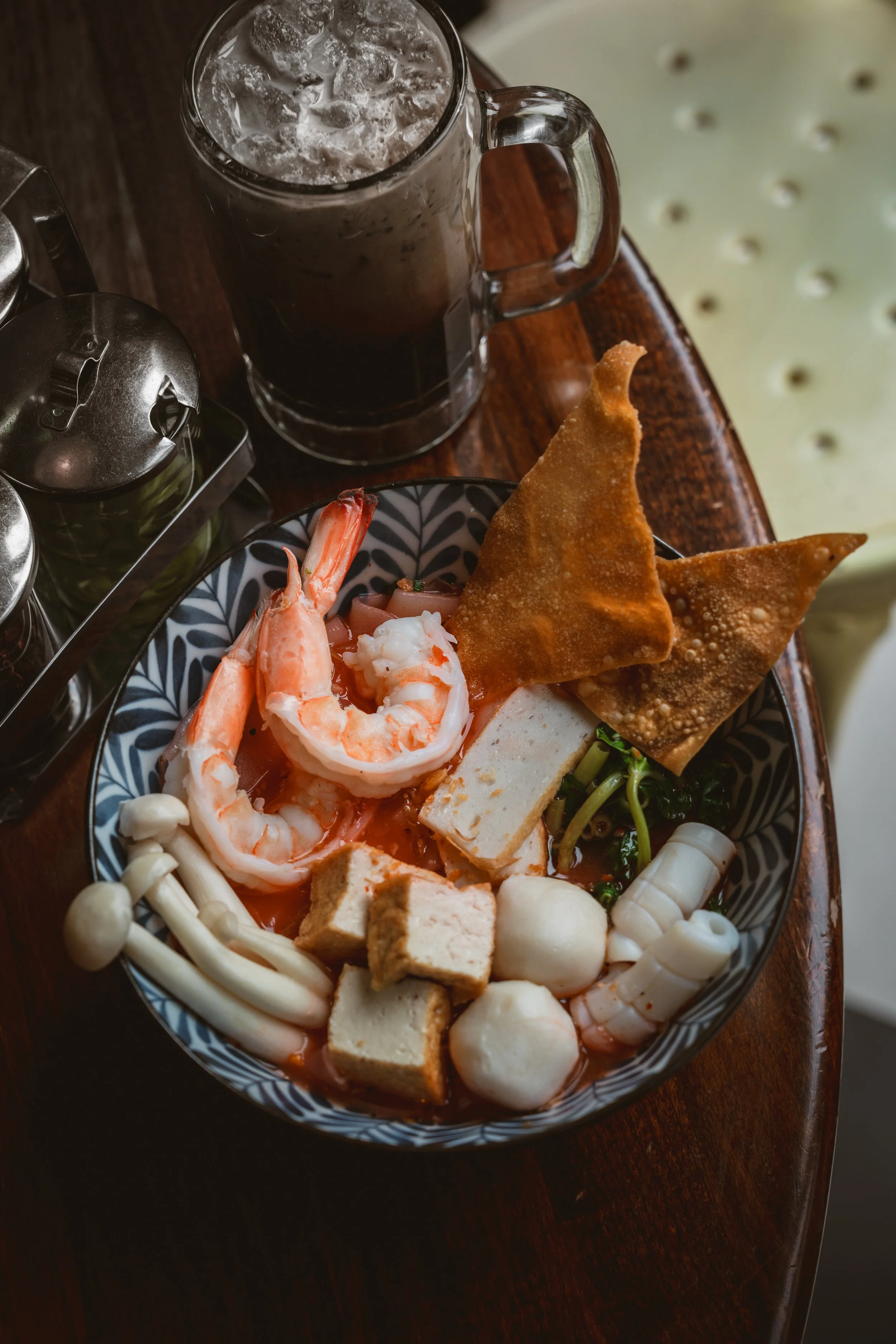 Krabi seafood noodles with shrimp, fish balls, tofu, fried wontons, and iced Thai coffee.