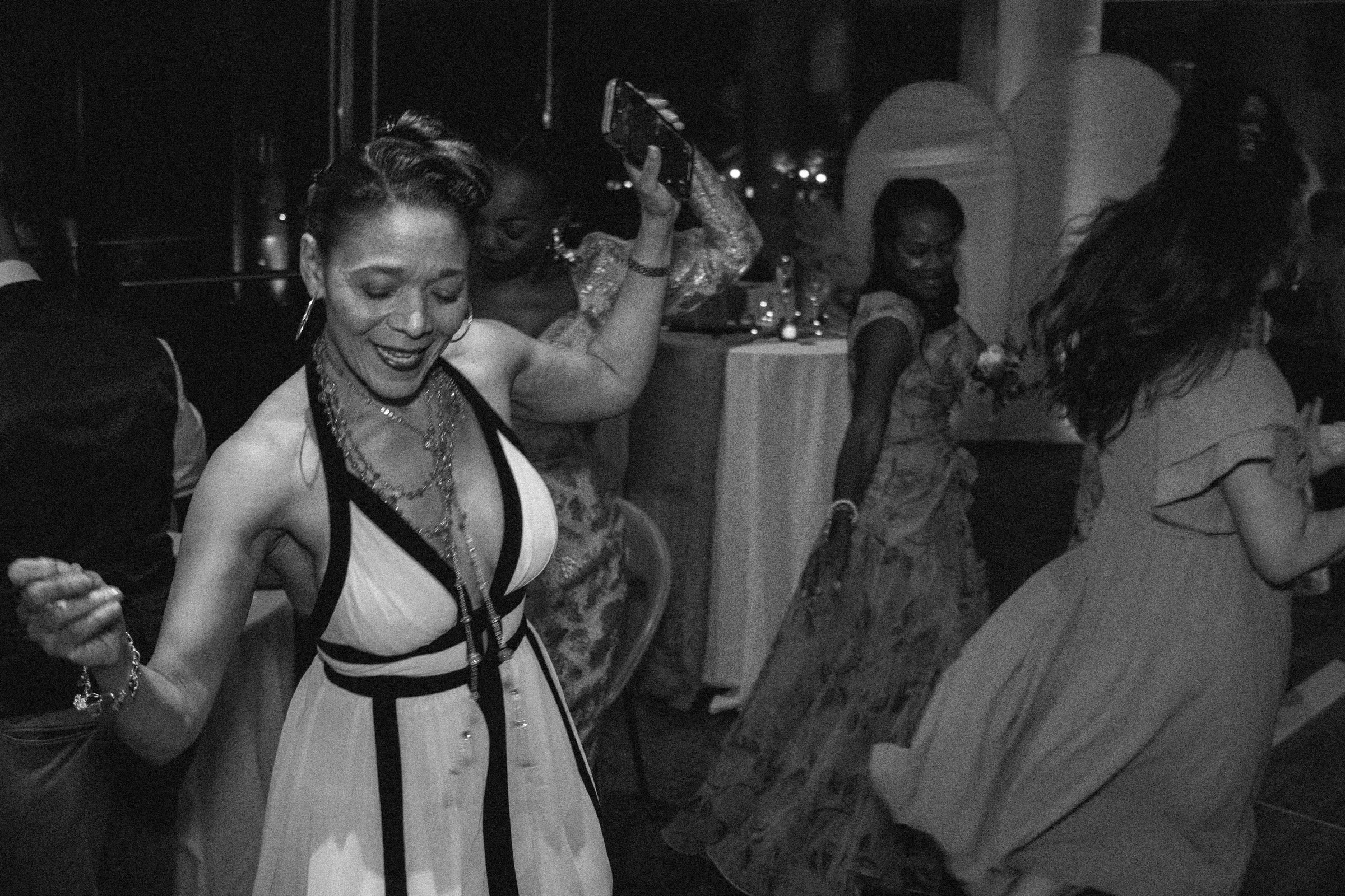 People dancing at a social event, with women smiling and enjoying themselves.