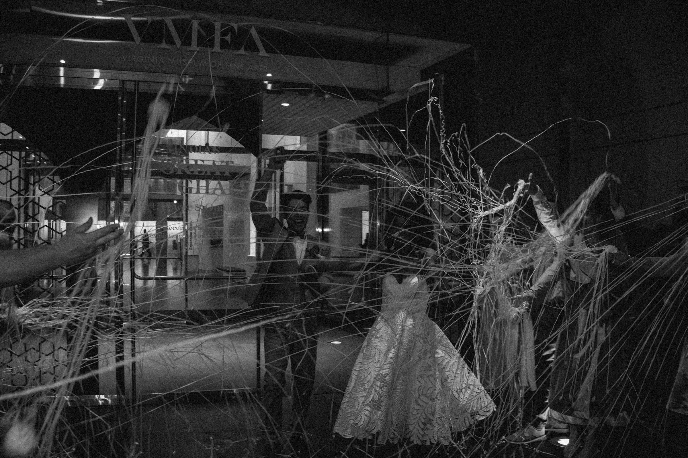 People inside the Virginia Museum of Fine Arts observing an art installation with fabric and string. The scene is captured in black and white.