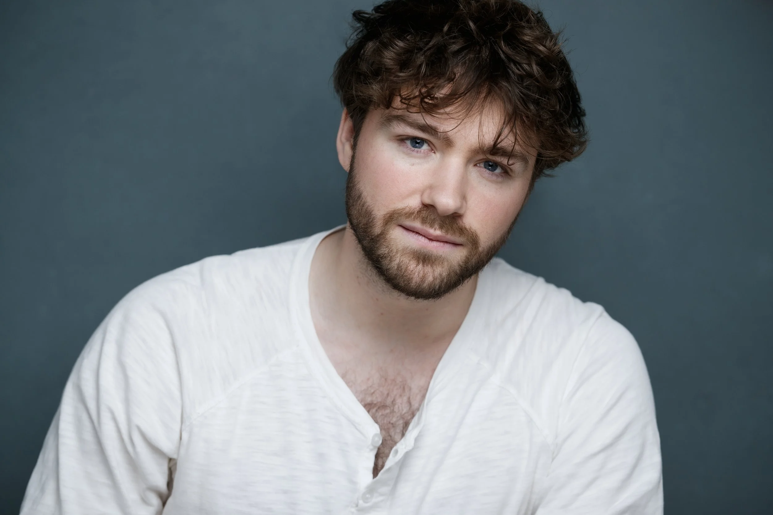 Raphaël Gareth portant une chemise blanche, se tenant contre un fond gris.