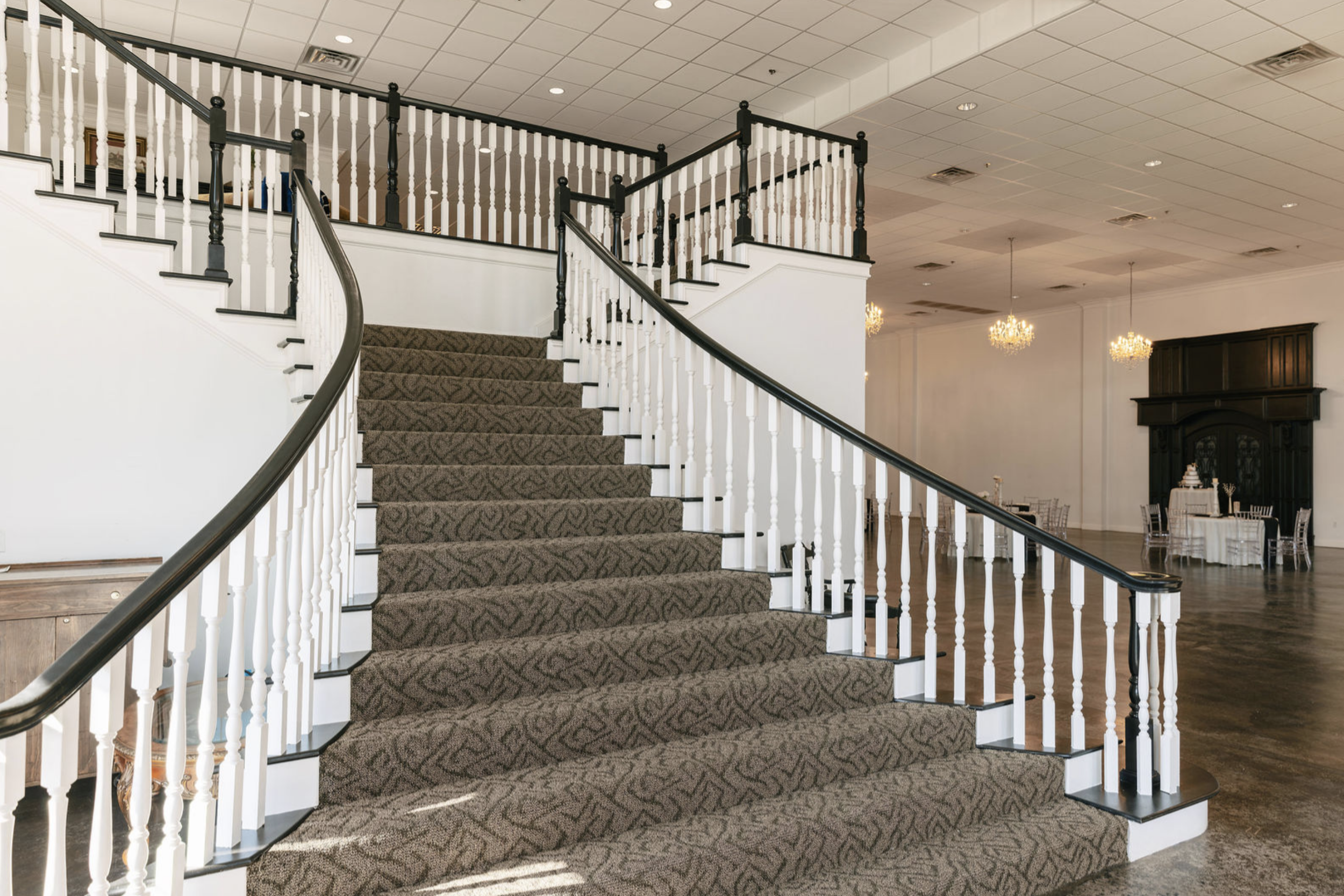 Elegant event venue featuring a grand curved staircase, classic railings, and open reception space ideal for weddings and events.
