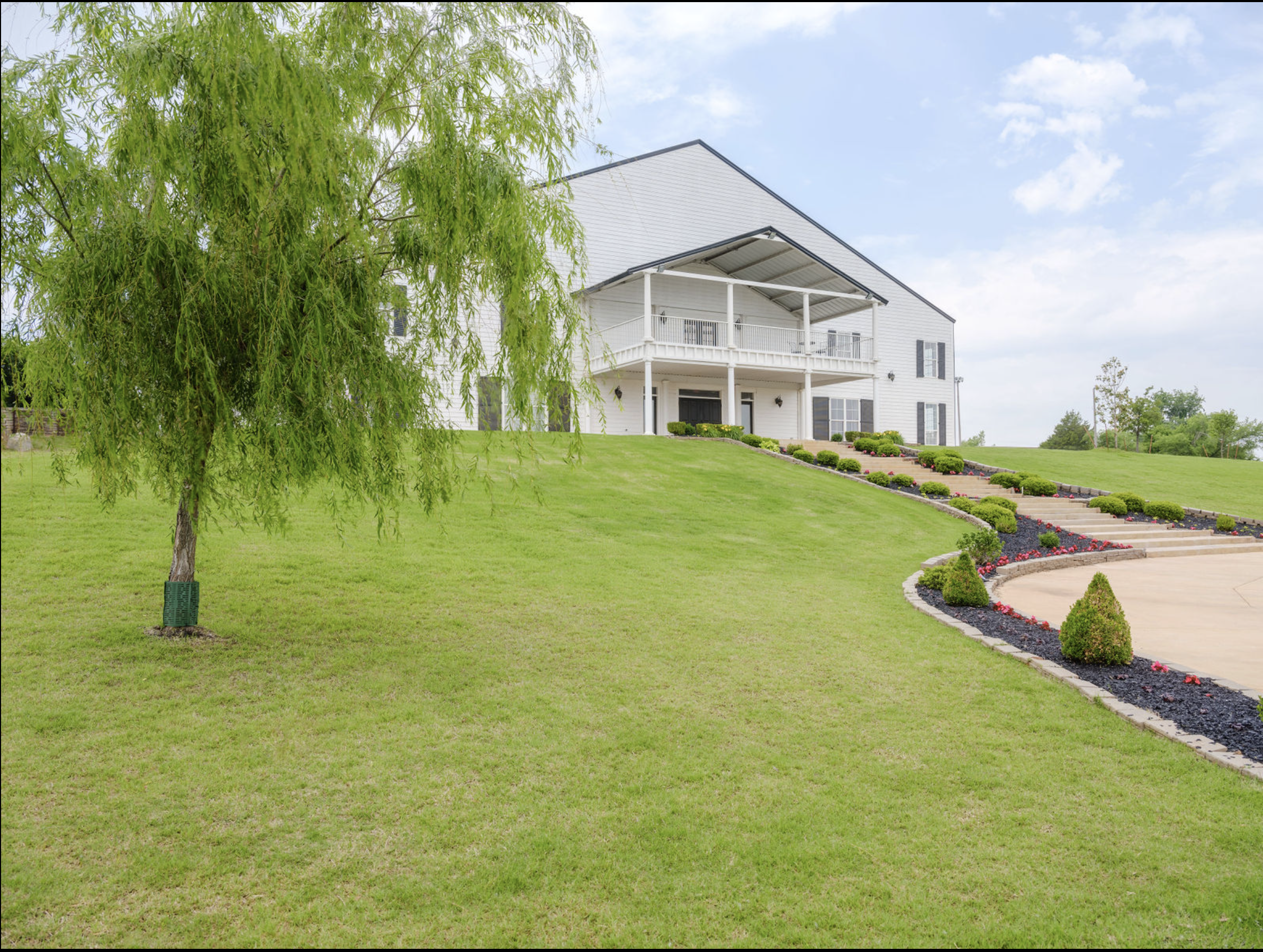 Beautiful exterior view of Coal Creek Event Center showcasing manicured landscaping, a sweeping driveway, and a grand white venue with covered balcony.