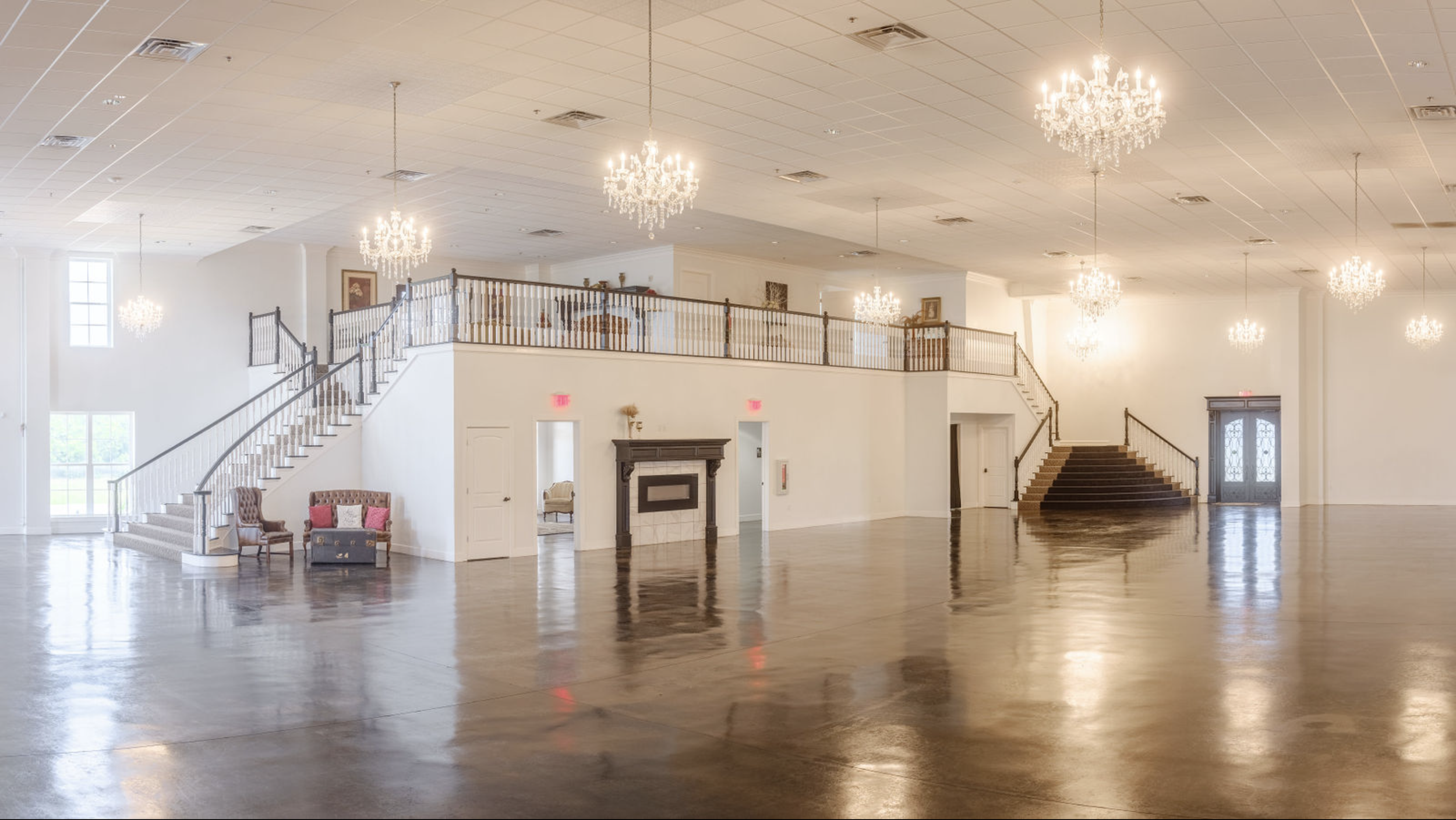 Spacious ballroom at Coal Creek Event Center featuring polished concrete floors, elegant chandeliers, grand staircases, and a versatile open layout for weddings and events.