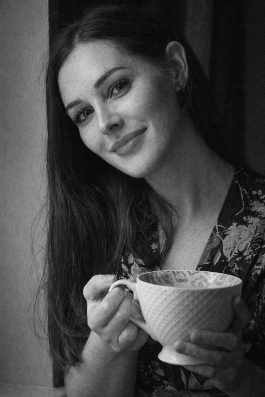 Ella is a professional counsellor and psychotherapist holding a patterned ceramic mug and smiling at the camera, in black-and-white photo.