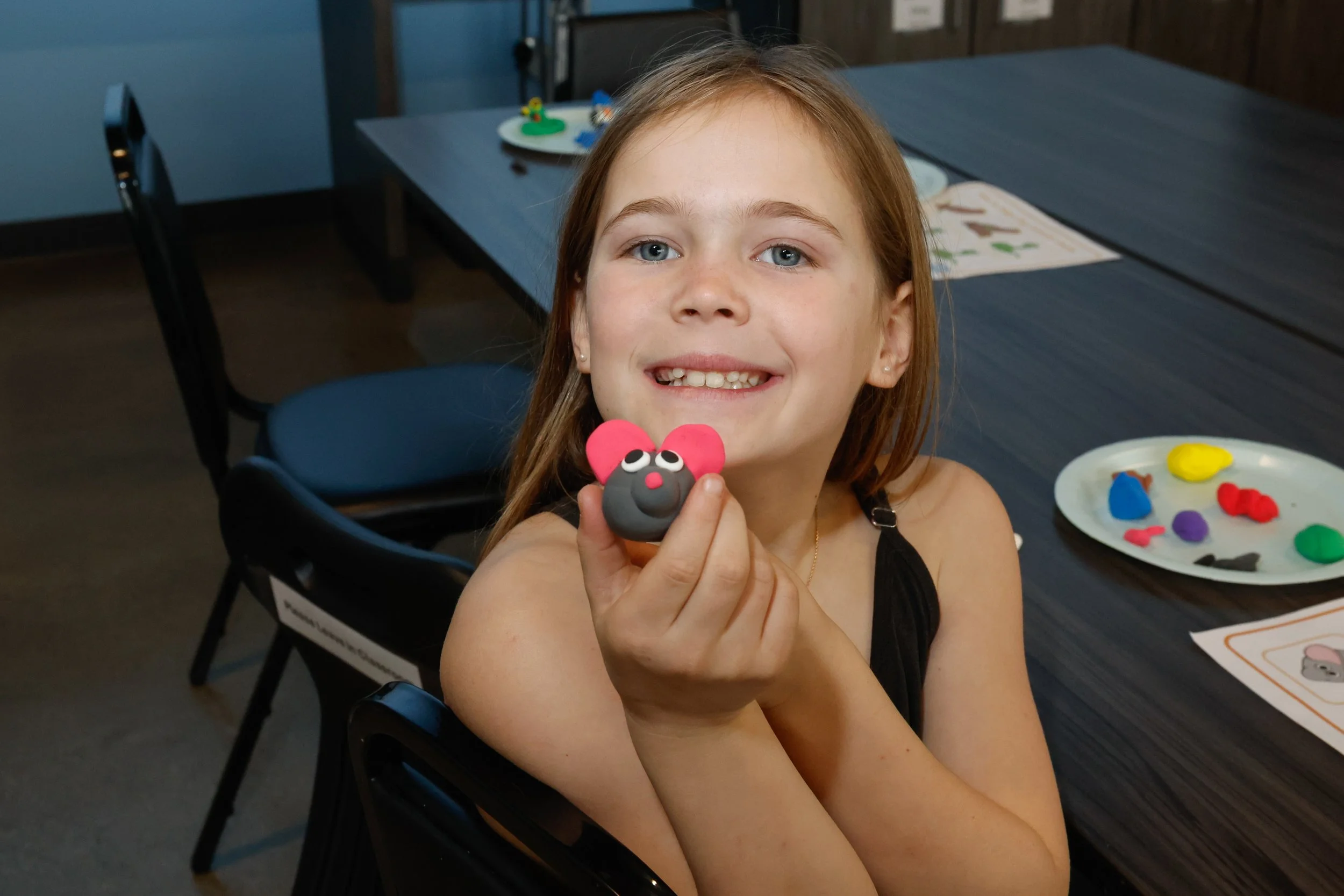 A kid making a sculpture mouse in art class.