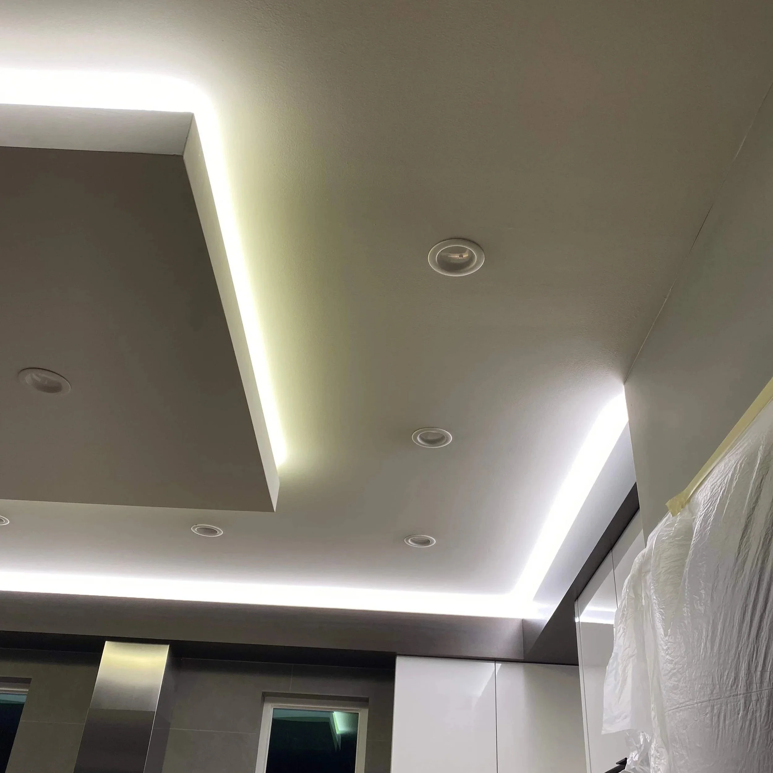 Ceiling with recessed lights and LED strip lighting on the edges, part of a modern interior space.