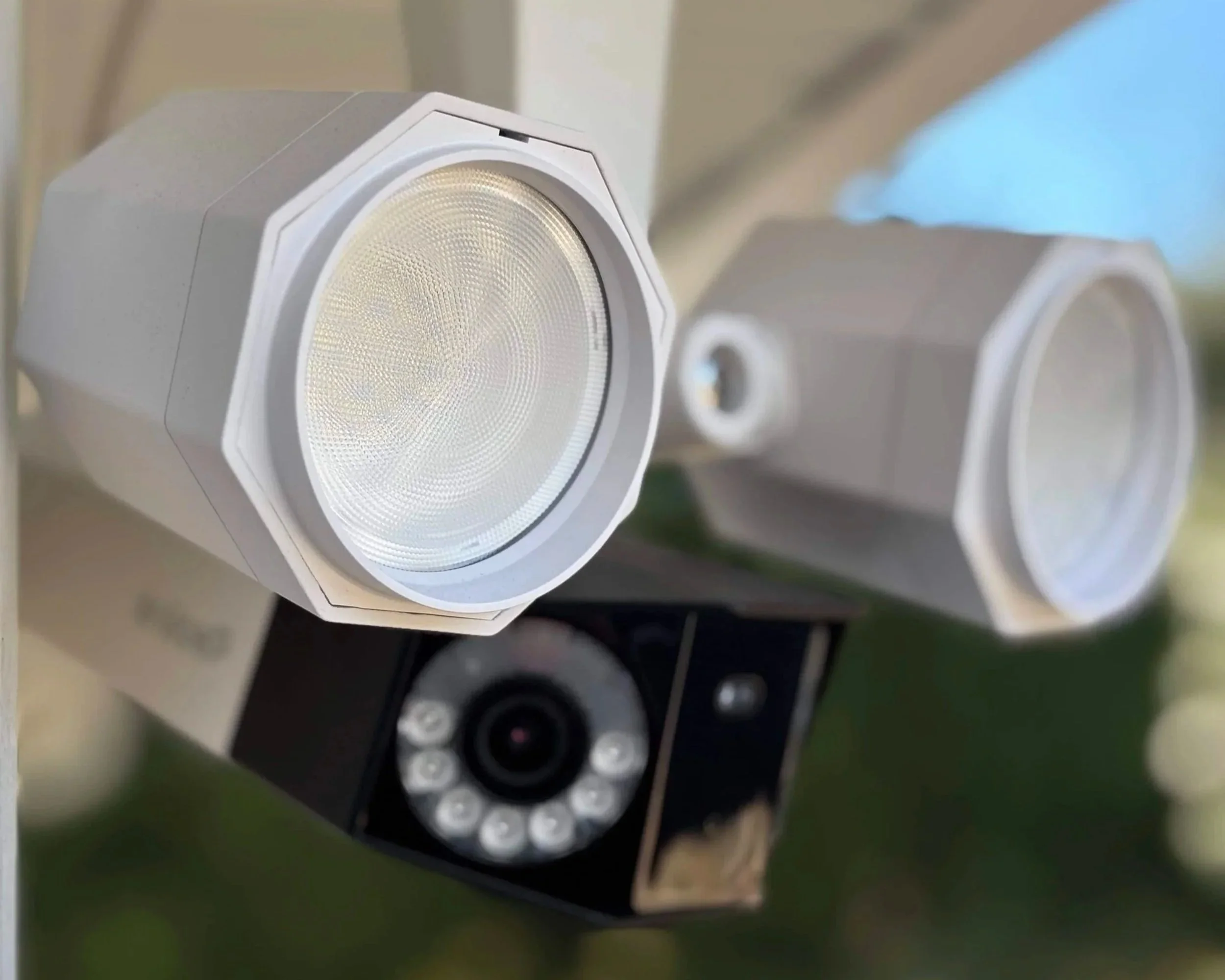 Outdoor security camera with two white CCTV cameras mounted on a pole. Demonstrating security lighting installation and landscape lighting installation.
