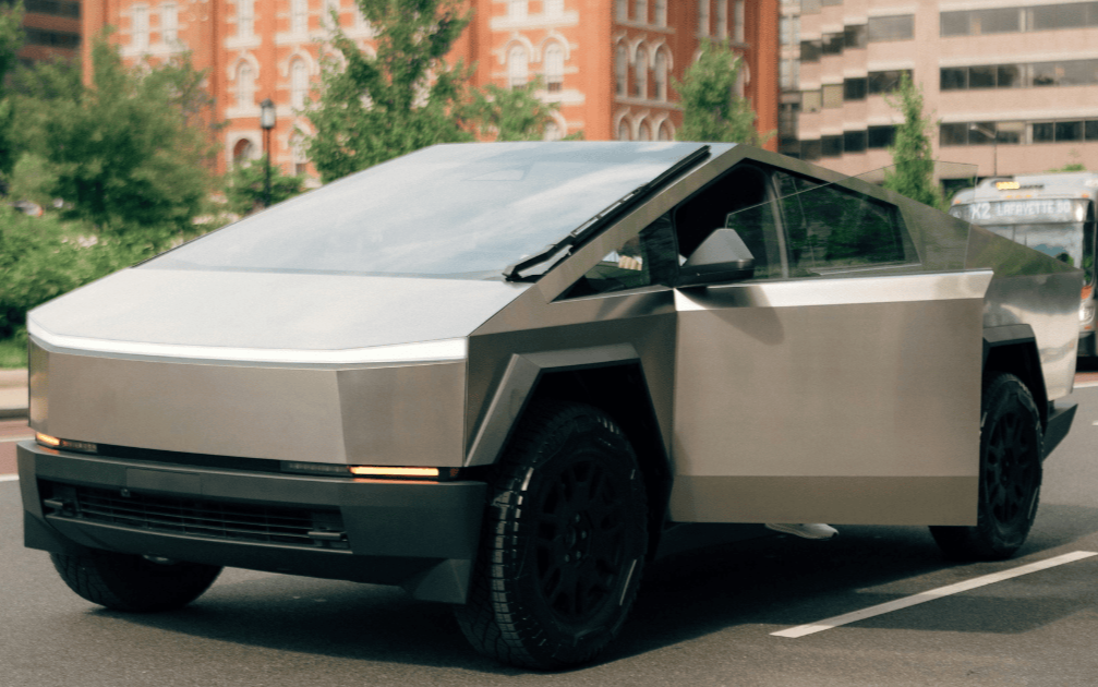 A futuristic, angular, two-tone electric car parked on a city street, with brick and modern buildings in the background.