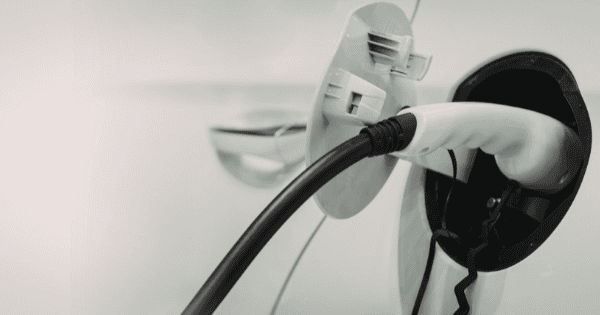 White electric vehicle being charged with a white charging plug, tesla home car charger