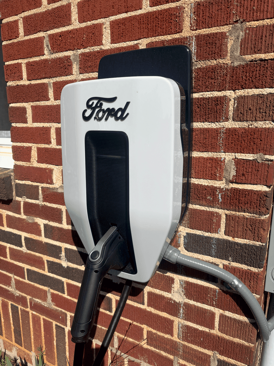 Electric vehicle charging station attached to a brick wall with the Ford logo.