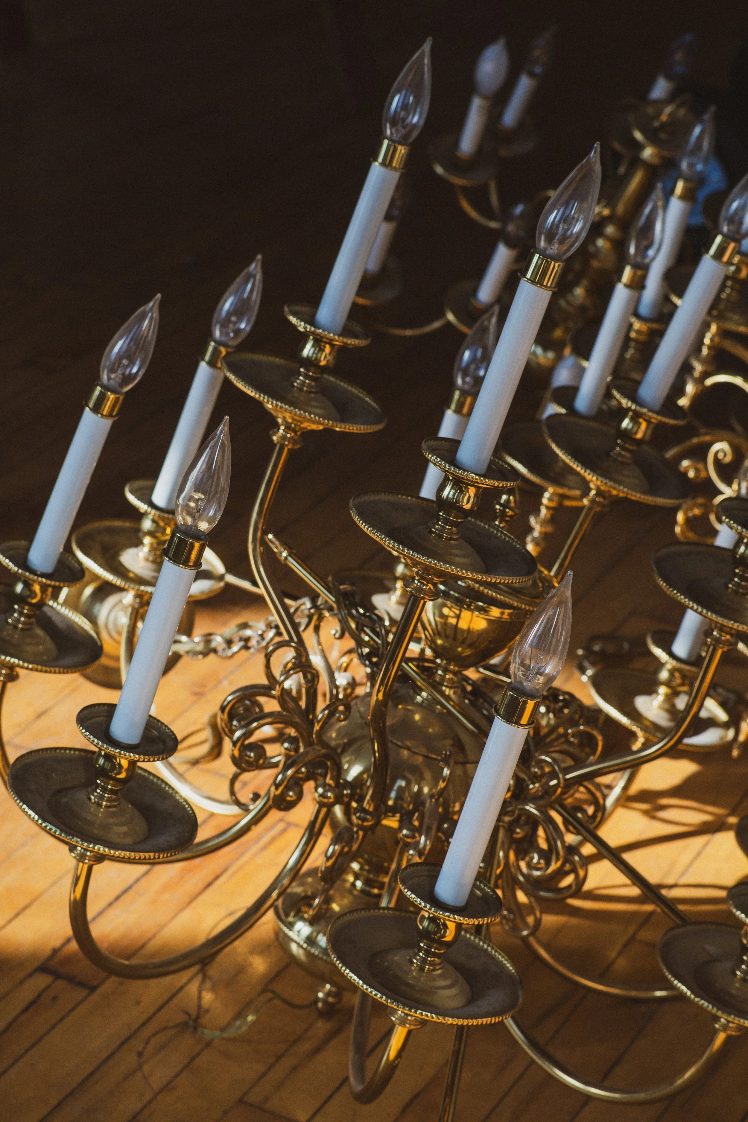 A gold chandelier with multiple candle-style lights on a wooden floor.