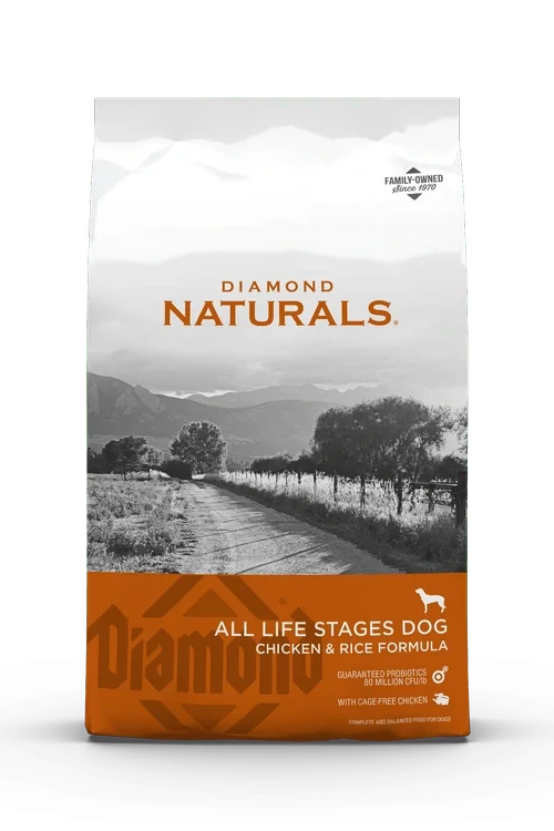 Front of a bag of Diamond Naturals Dog Food with a black and white mountain landscape and a dirt road. The label indicates it's for all life stages, chicken and rice formula, with guaranteed probiotics and cage-free chicken.
