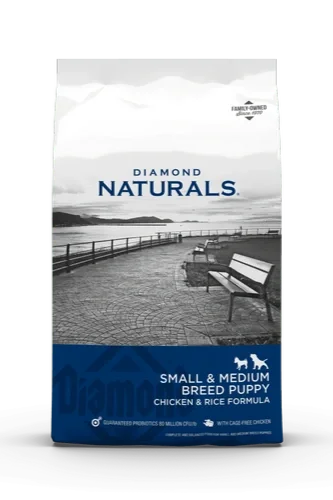 Bag of Diamond Naturals small and medium breed puppy dog food with chicken and rice formula, featuring an outdoor lakeside scene with benches and a pier.