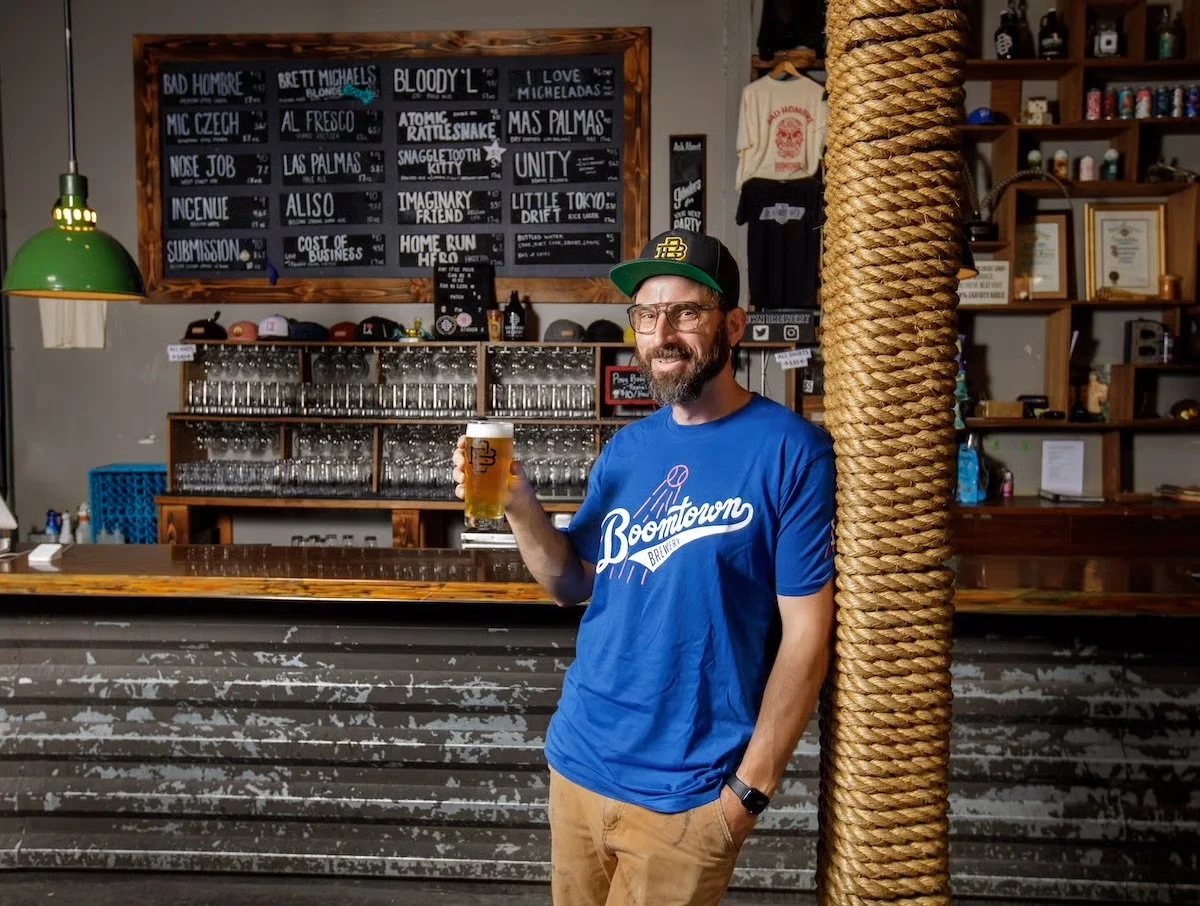 Head brewery standing in front of bear wearing a blue Boomtown shirt that looks like an LA Dodgers shirt