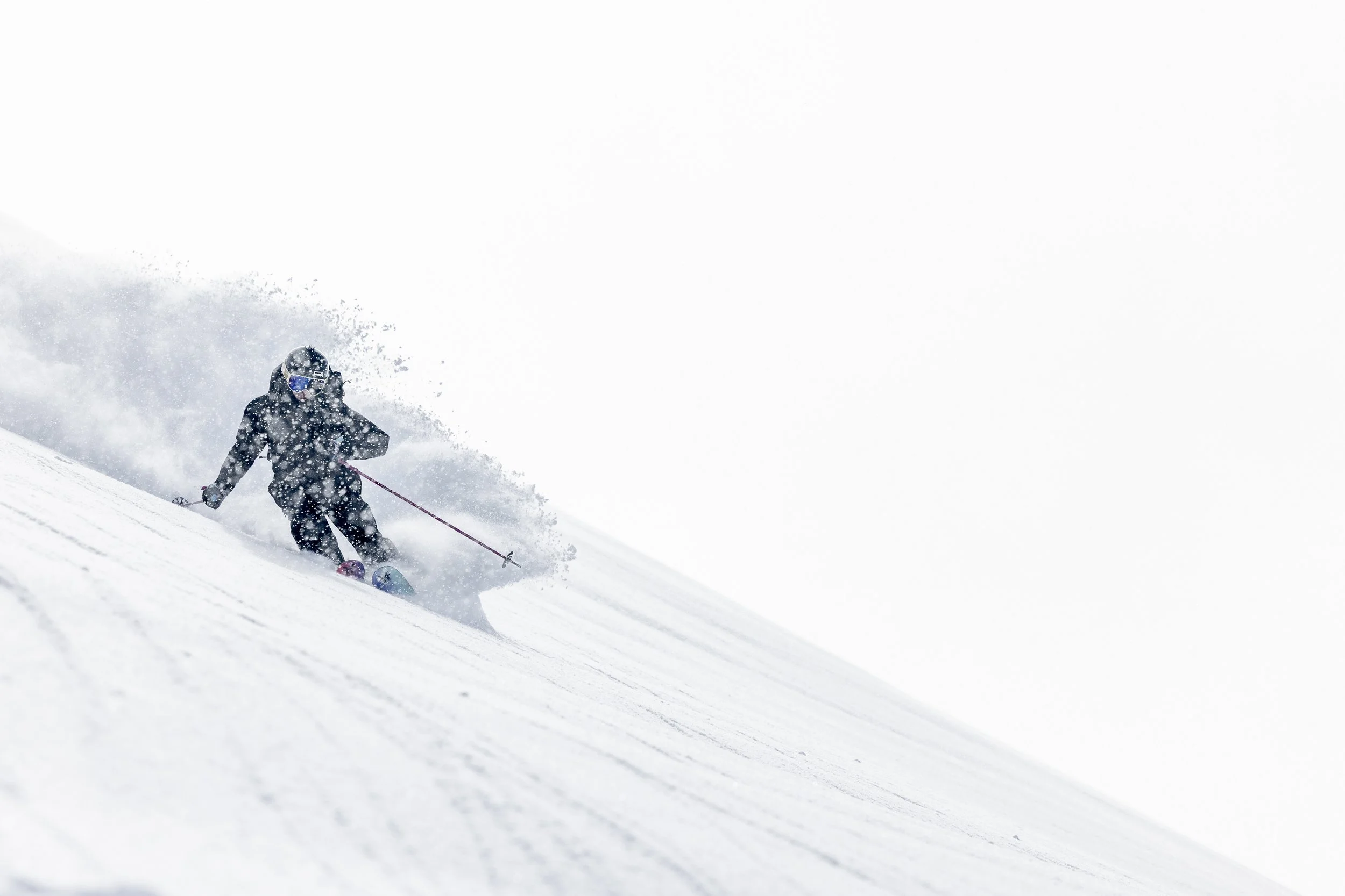 Sciatore che scende una pista innevata con neutroni di neve che sprigionano, sotto un cielo bianco