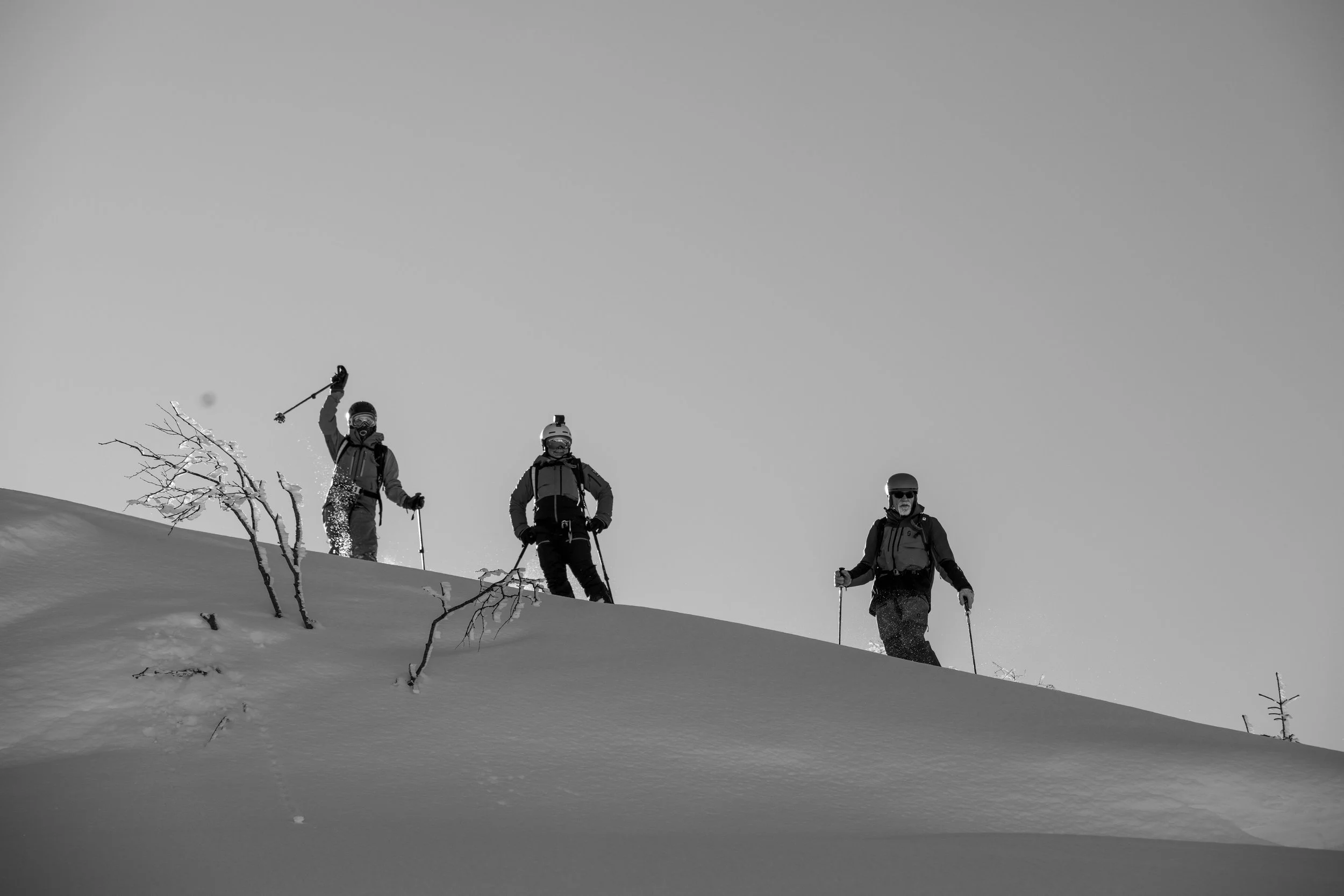 Tre escursionisti con equipaggiamento da montagna sulla neve in un paesaggio invernale, in piedi su una pendenza.