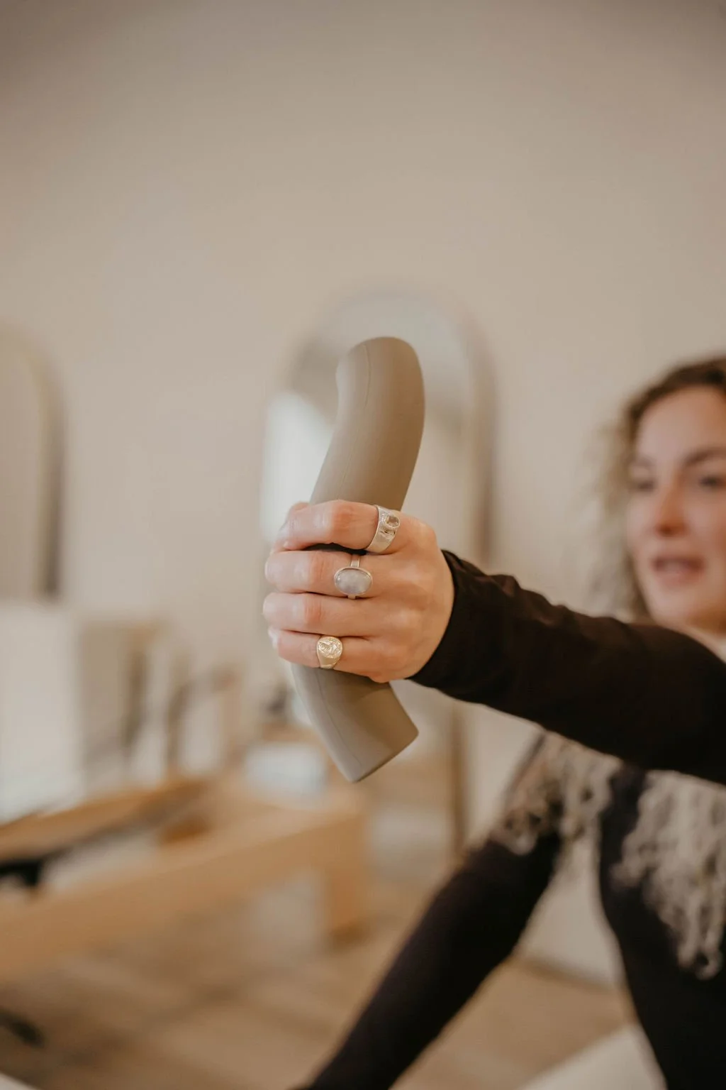 A woman holding a vintage beige telephone receiver in a room with blurred background.