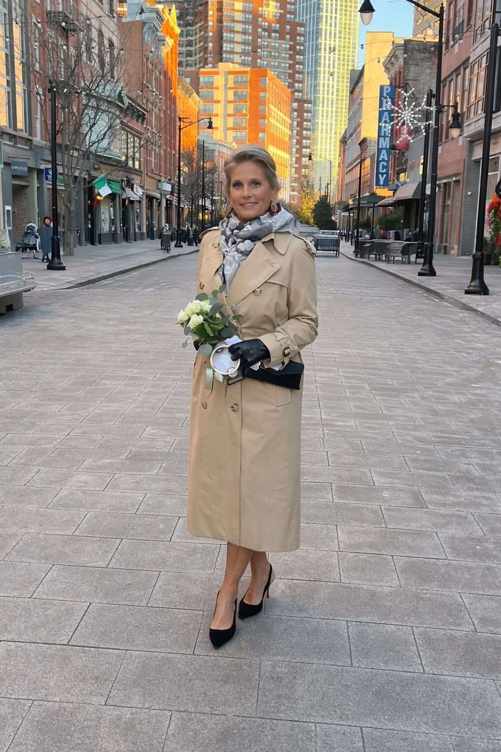 Owner, Elizabeth, standing on a busy street holding a bouquet of flowers wearing a brown trenchcoat