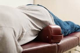 Person lying on an examination table with pelvic blocks during an adjustment.
