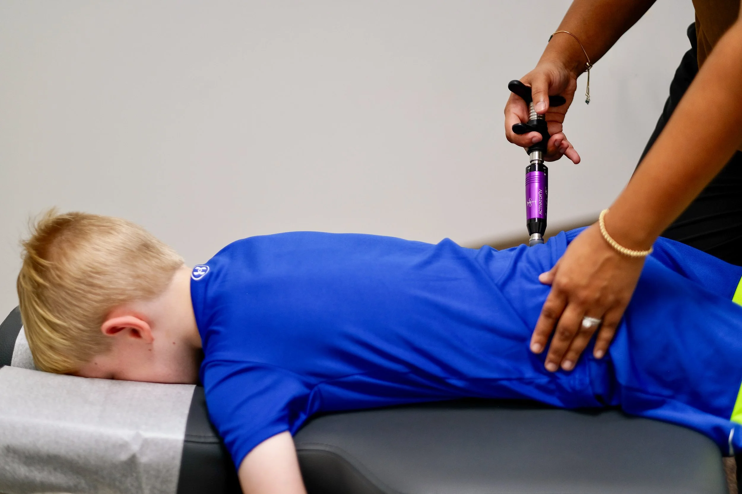 Dr. Shivani Patel gently adjusting a young child's spine with a low-force instrument, pediatric chiropractic in Franklin and Brentwood, TN