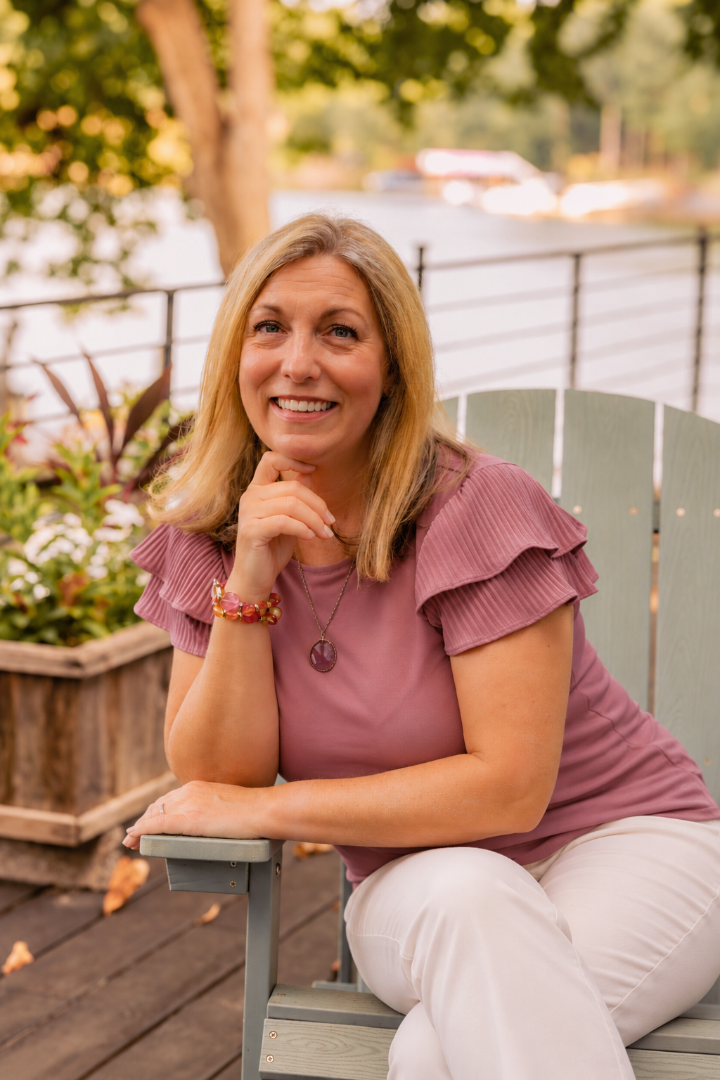 smiling woman sitting with lake behind her