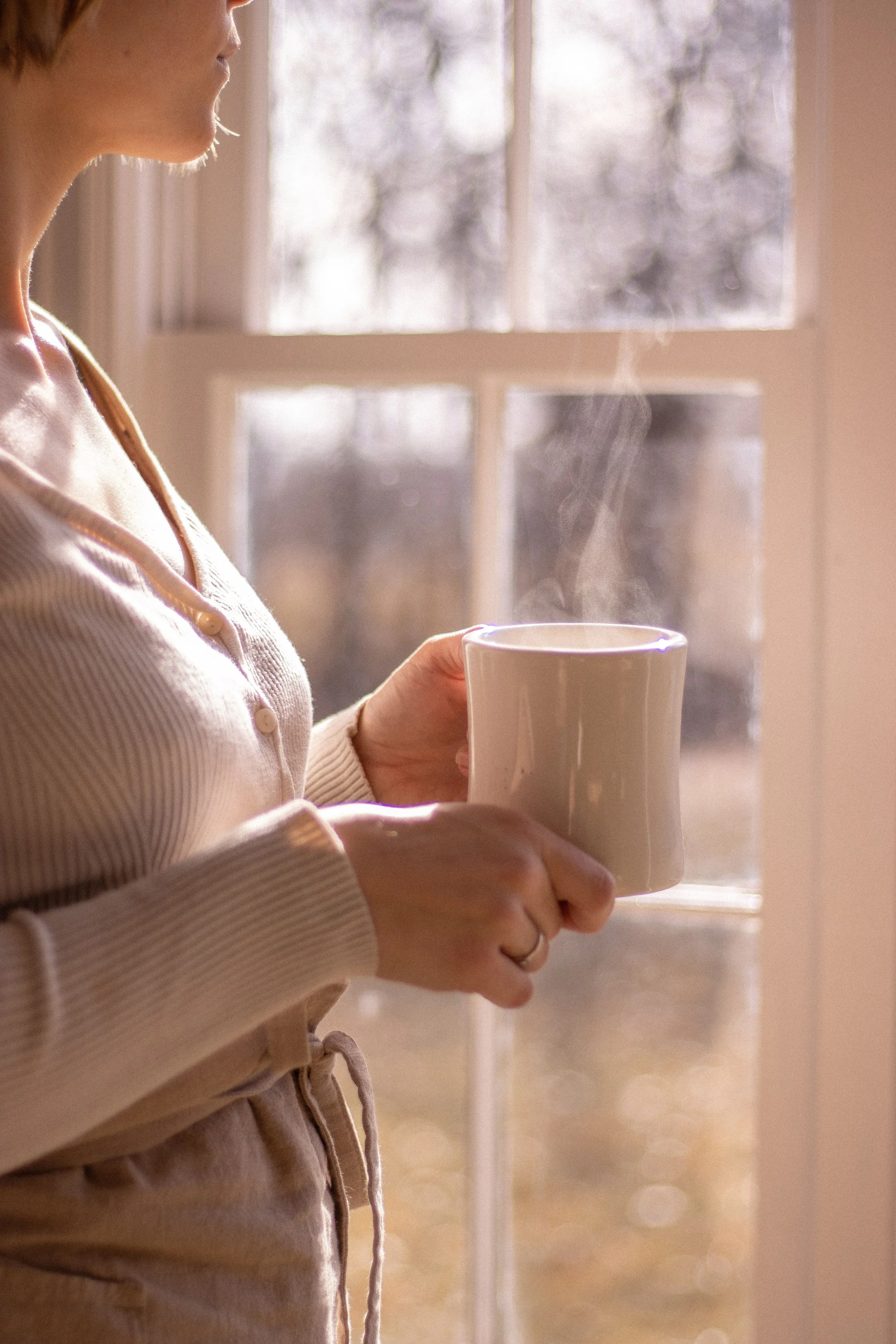 woman with coffee mug beside window