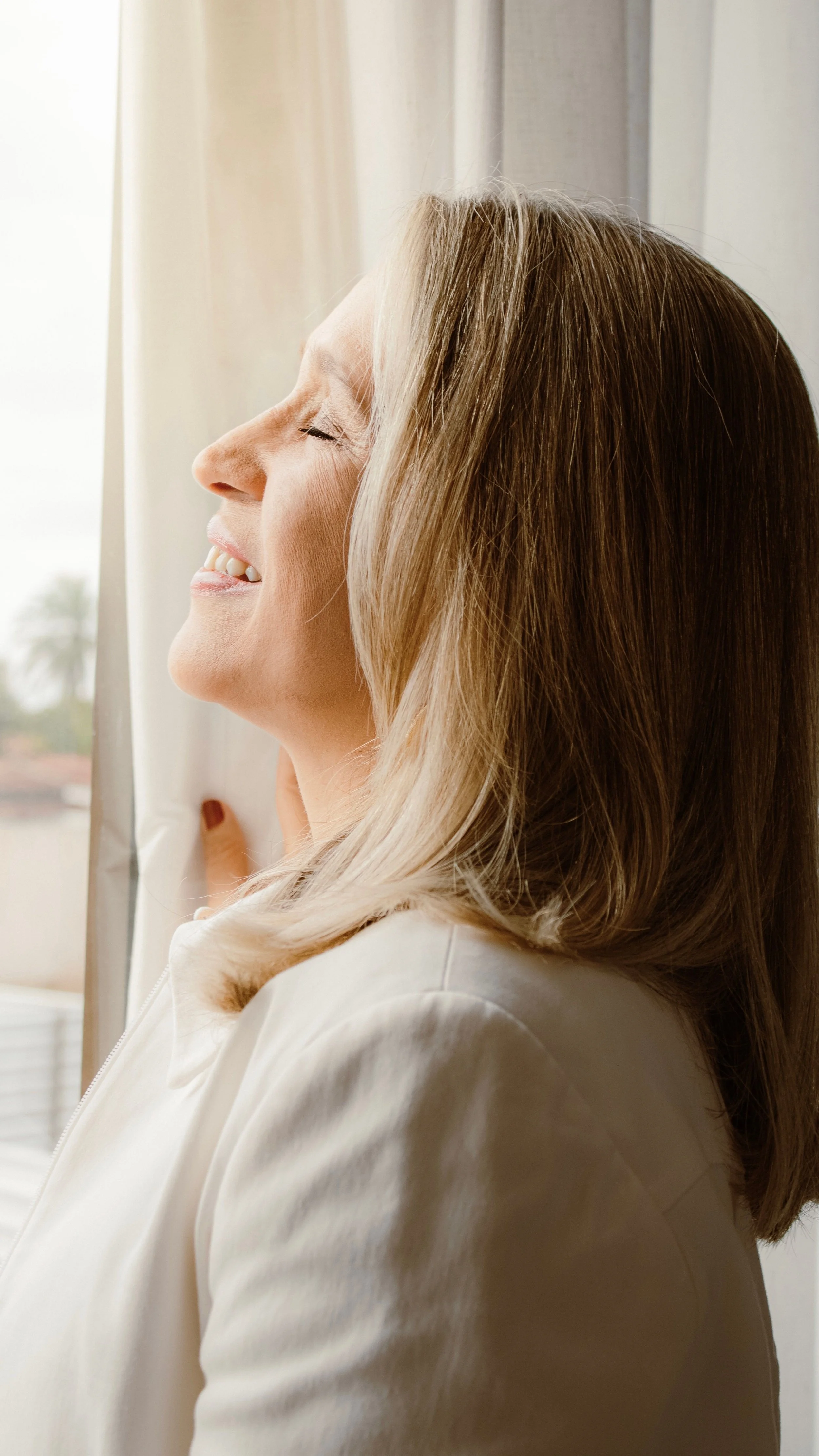 relaxed smiling woman beside window