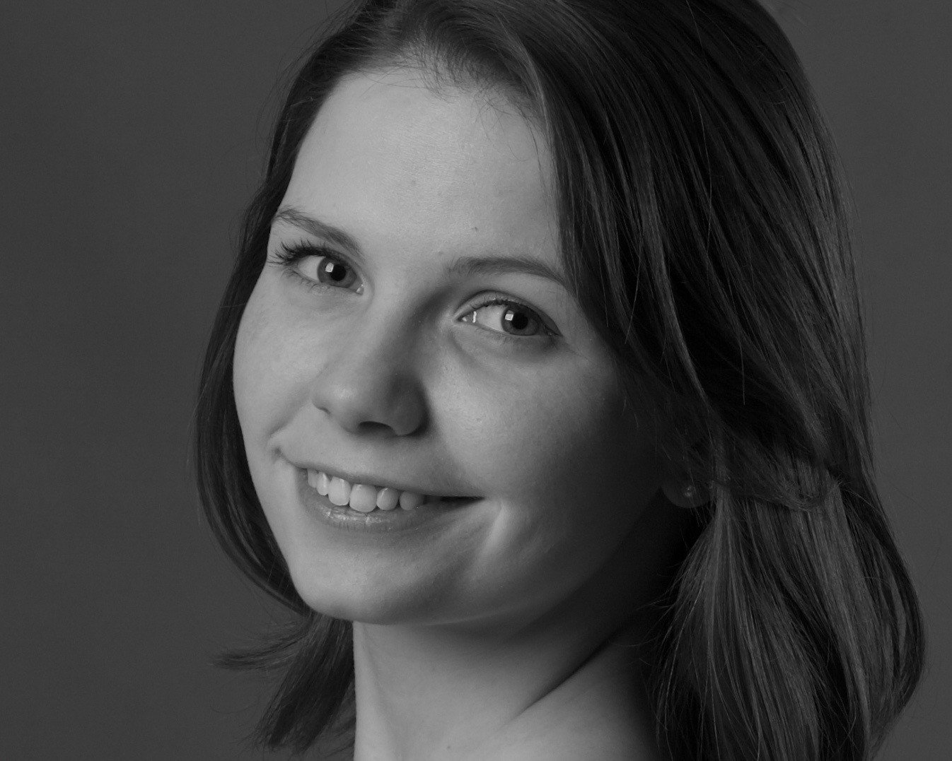 Black and white portrait of a young woman with shoulder-length hair, smiling, facing slightly to the right