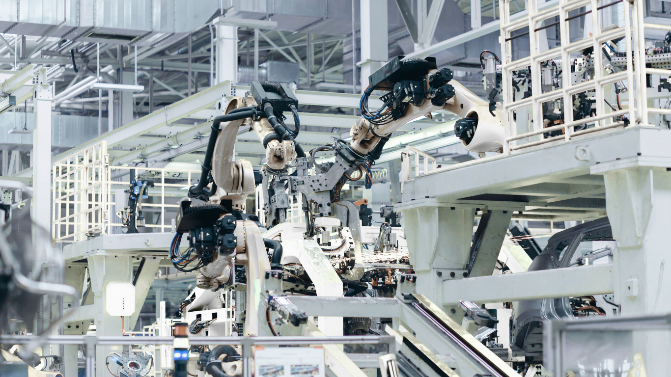 Industrial robotic arms working on a car assembly line in a factory.