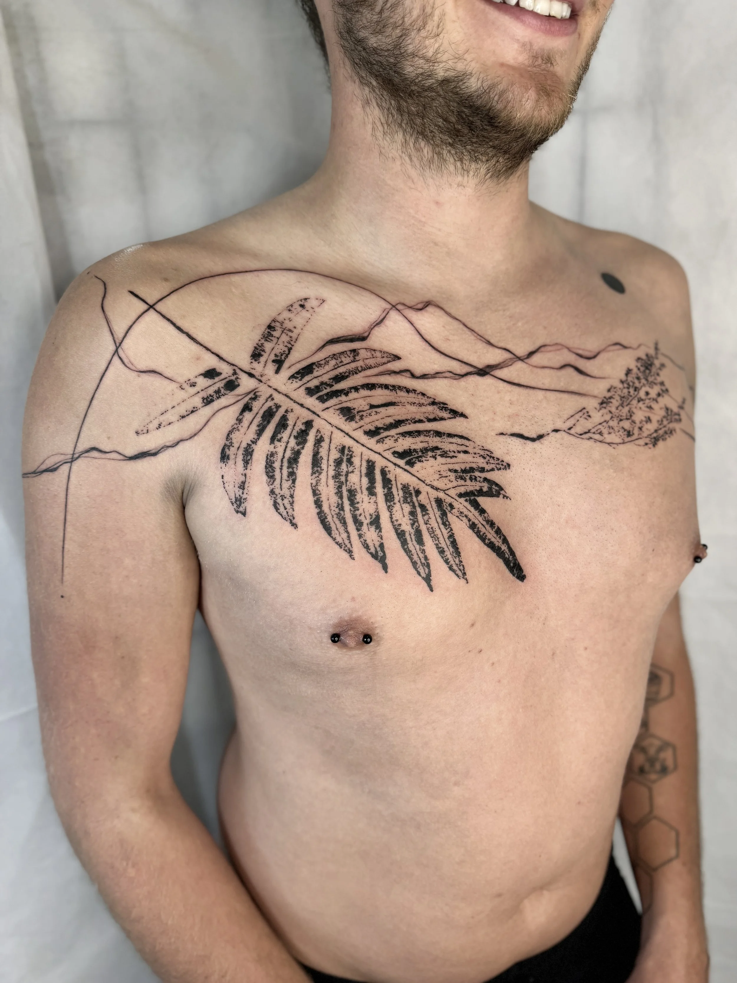 Tattoo of an abstract mountain landscape and a large black fern imprint and geometry. Unique BC travel tattoo