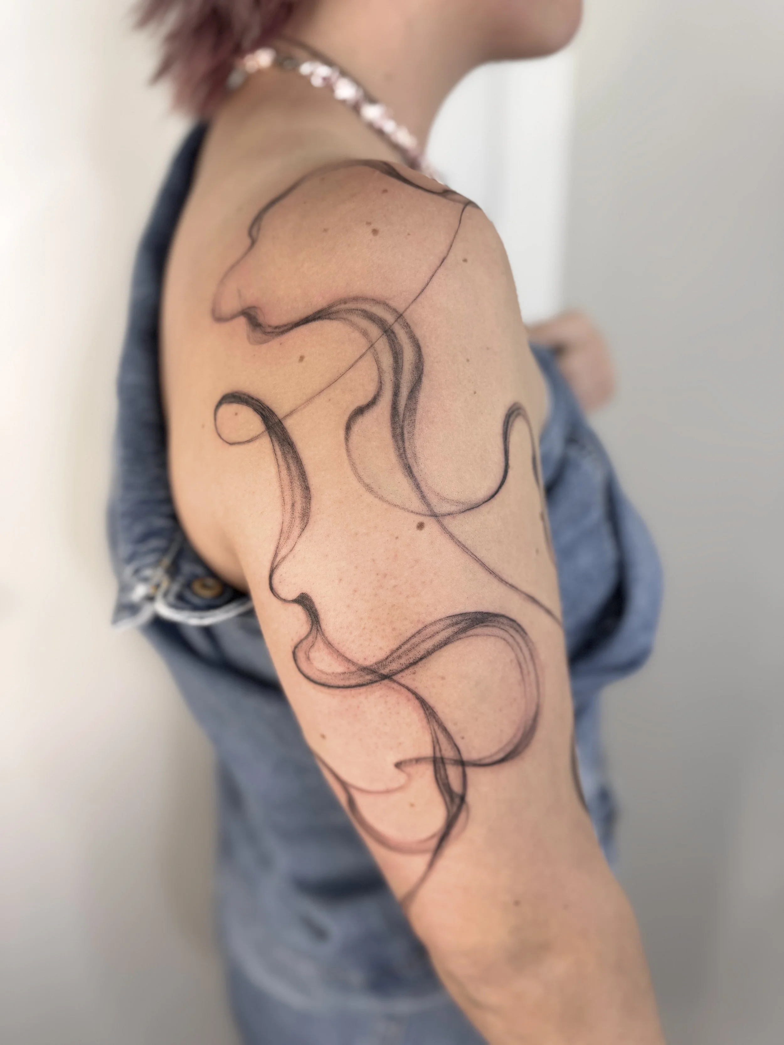 Tattoo of a smoke texture on a person's upper arm and shoulder. Abstract tattoo