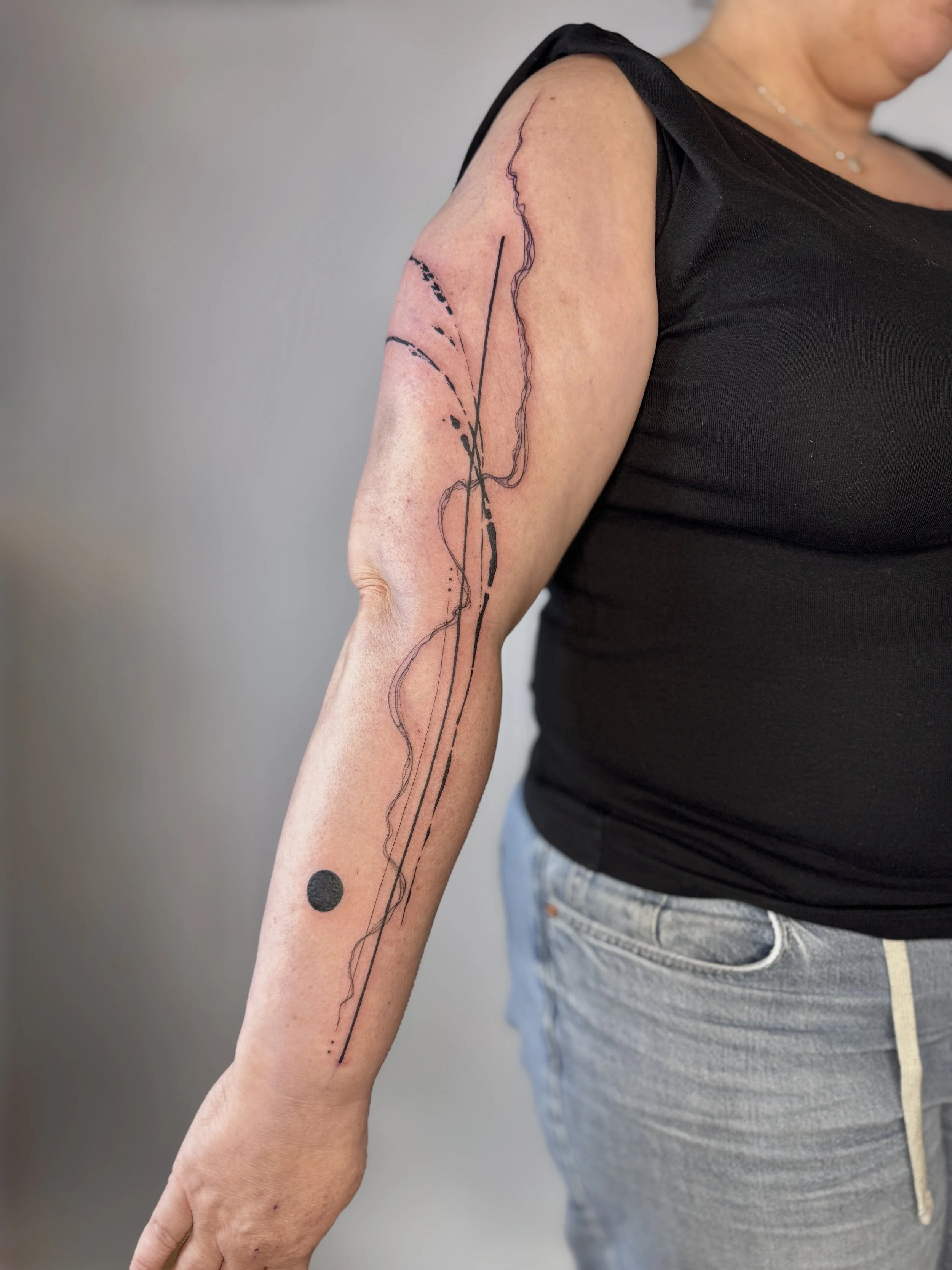 Tattoo of abstract line art and black dot on woman's forearm. Abstract tattoo composition inspired by nature and texture, fine line tattoo Vancouver