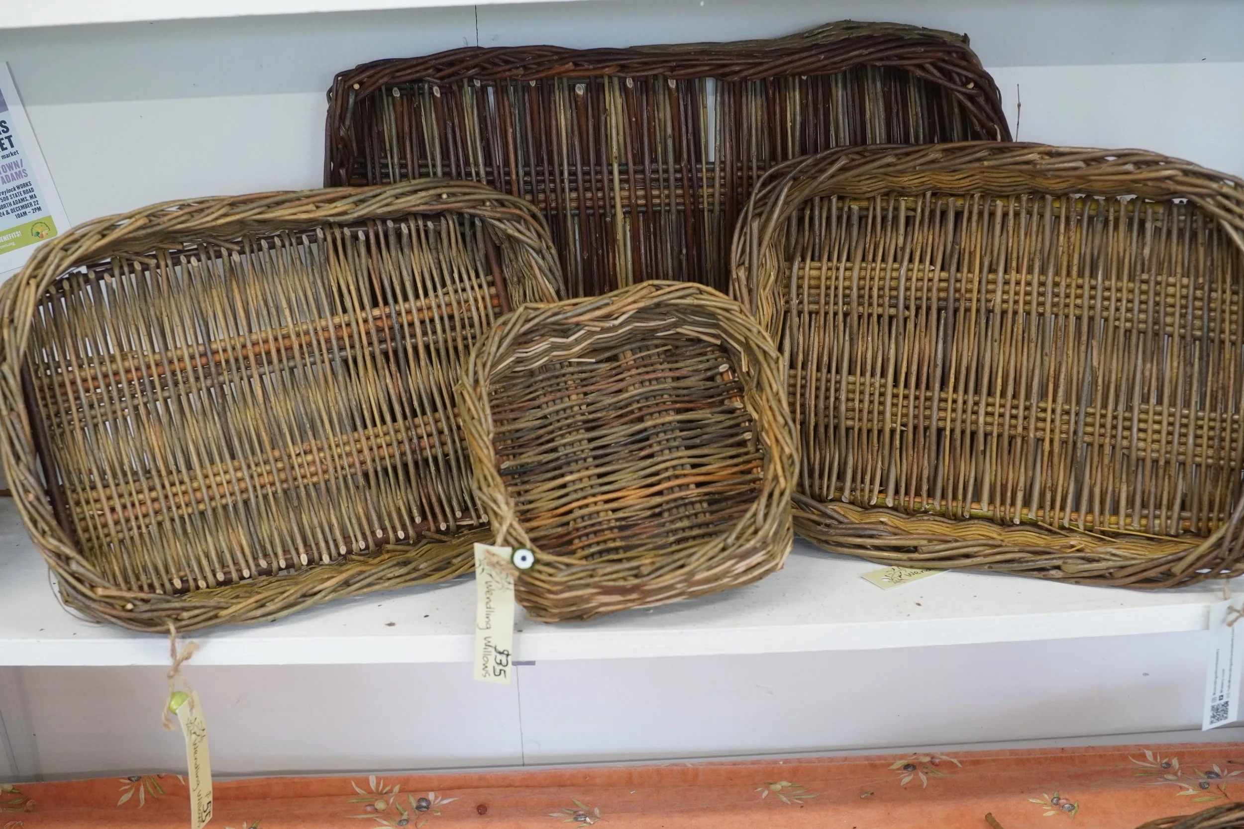 Several woven wicker baskets on a store shelf, with price tags attached.