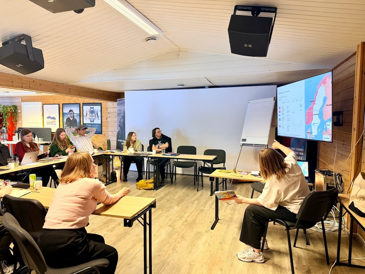 Participants in a workshop session with a map of the Nordic region displayed on a screen at the front of the room