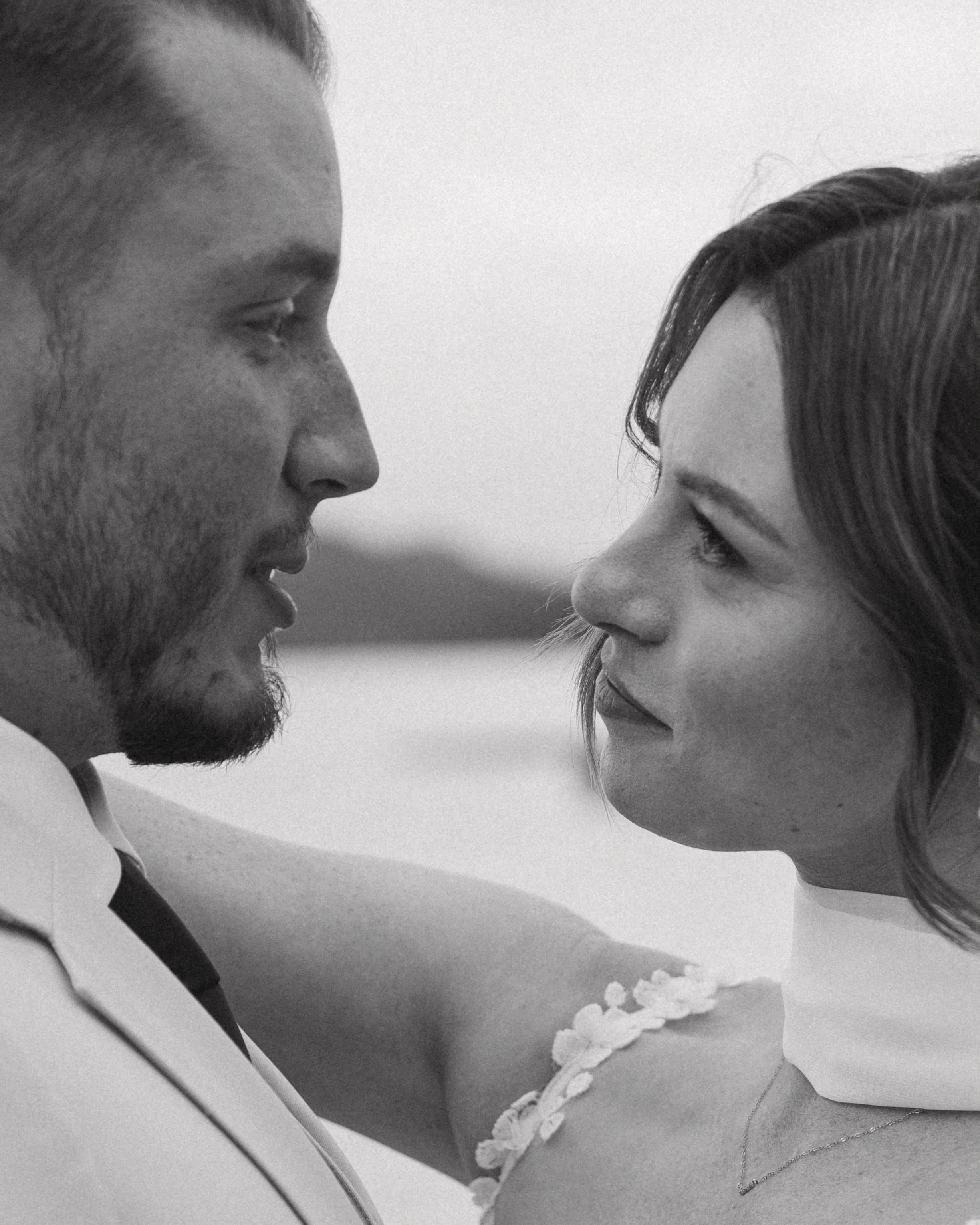 A black and white close-up of a man and a woman gazing into each other's eyes with their faces very close.