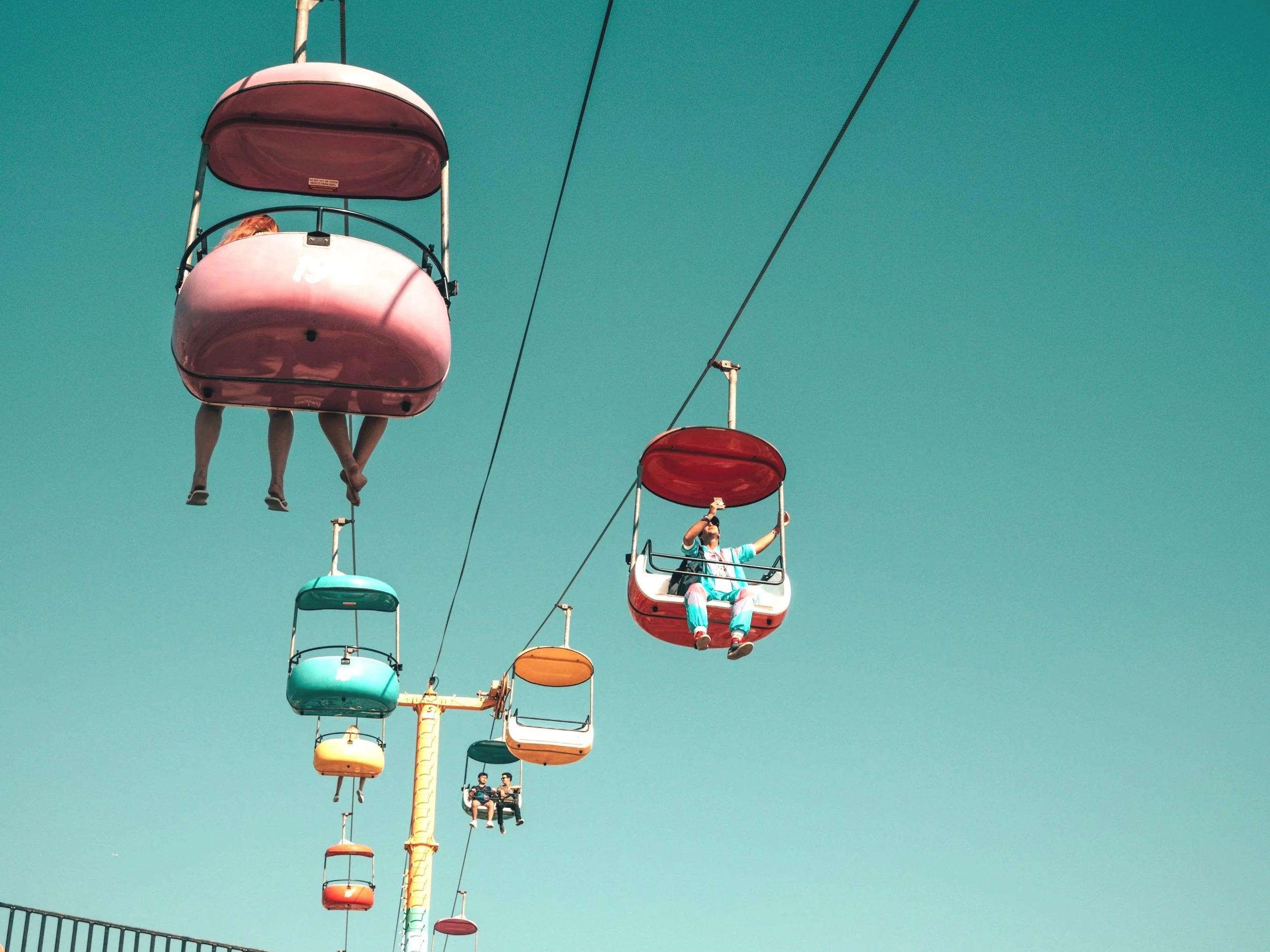 Menschen sitzen in bunten Gondeln eines Riesenrads bei klarem Himmel.