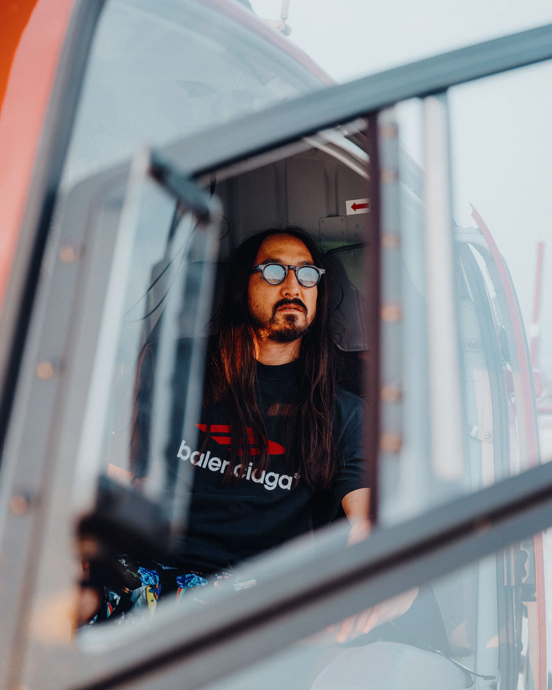 Steve Aoki taking inside the cockpit of a helicopter, looking outward through the window taken by James Bridle Music Photographer. 