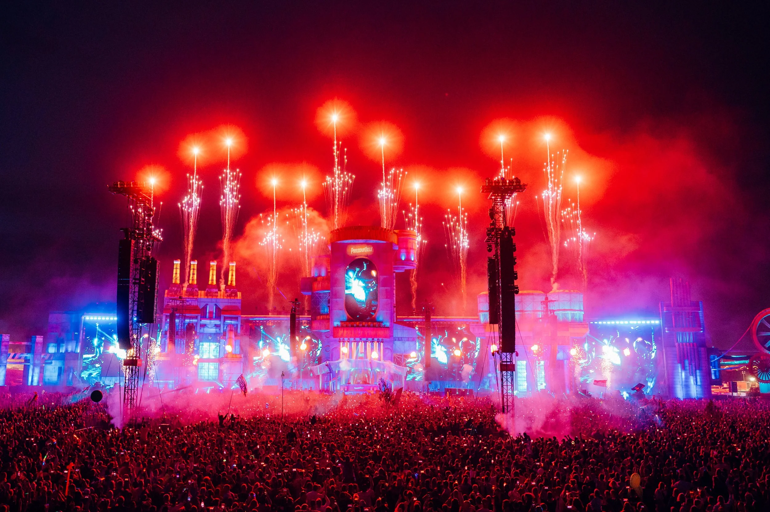 Steve Aoki performs at Parookaville Festival, Weeze, Germany showing a large crowd at night, with fireworks exploding over a brightly lit stage with colourful visuals. Taken by James Bridle music Photographer.