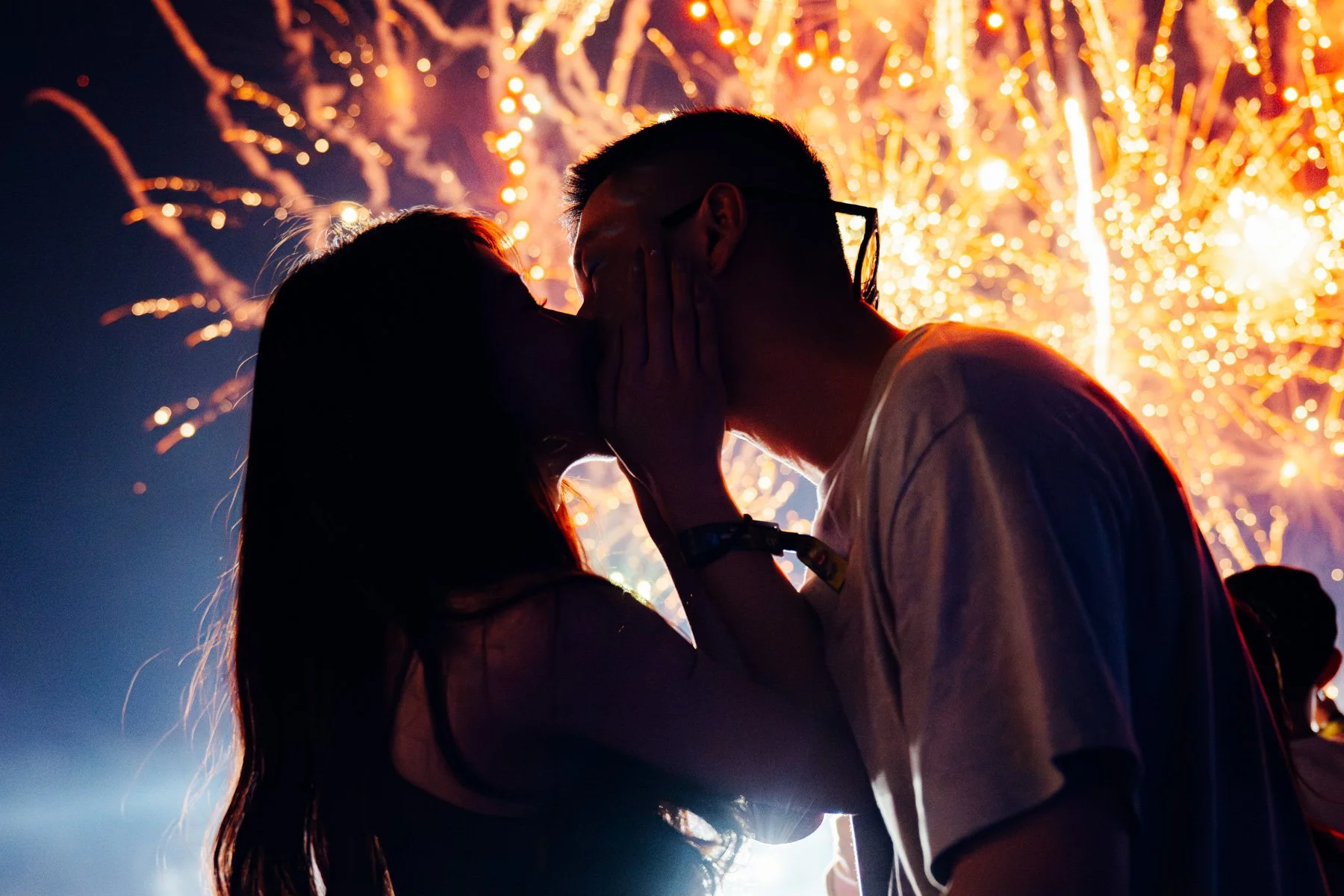 Neon Countdown Bangkok 2023 - A silhouette of a couple kissing at night during a fireworks display.