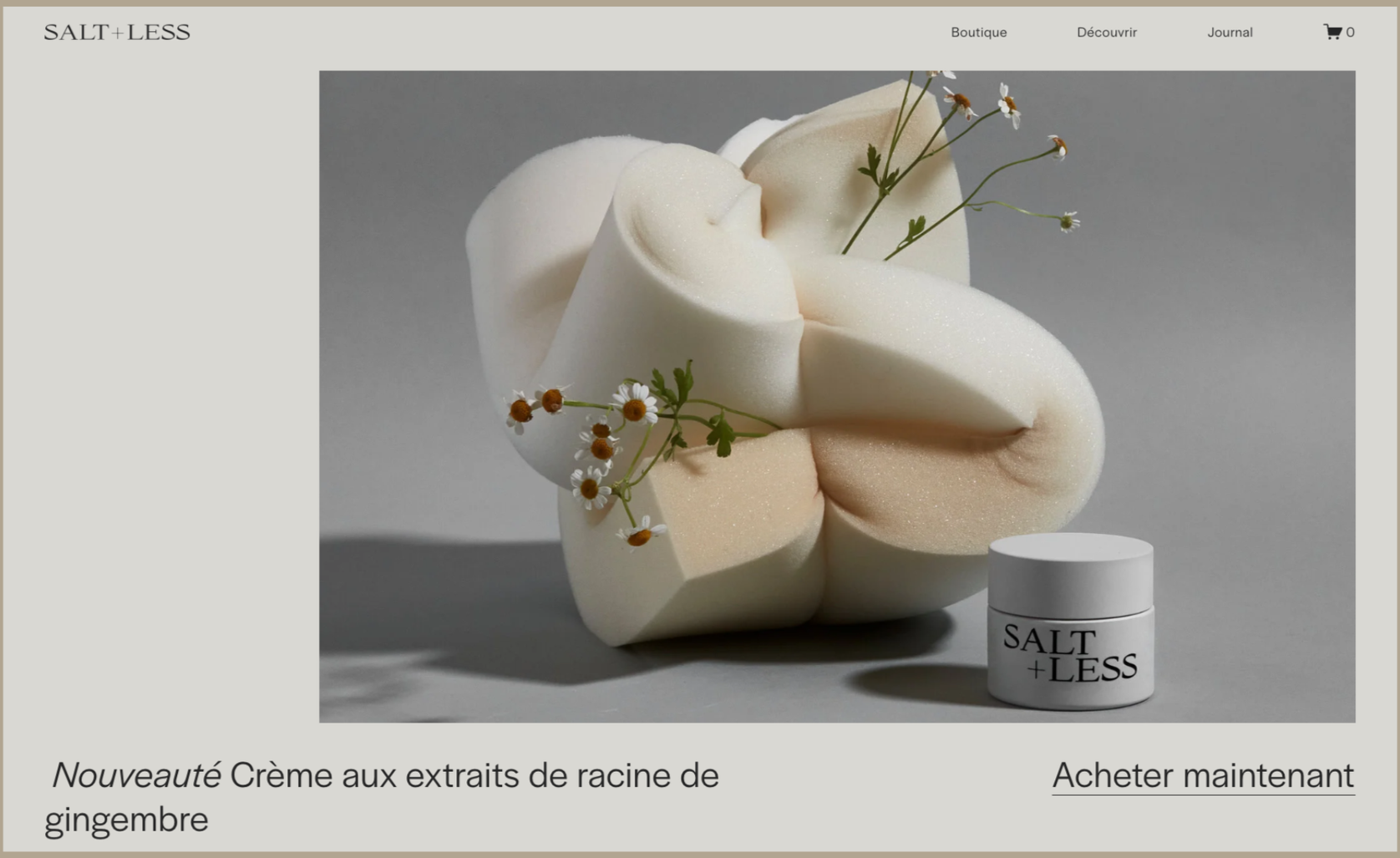 Une crème dans un pot blanc avec l'inscription 'SALT + LESS', entourée de morceaux de mousse et de petites fleurs blanches.