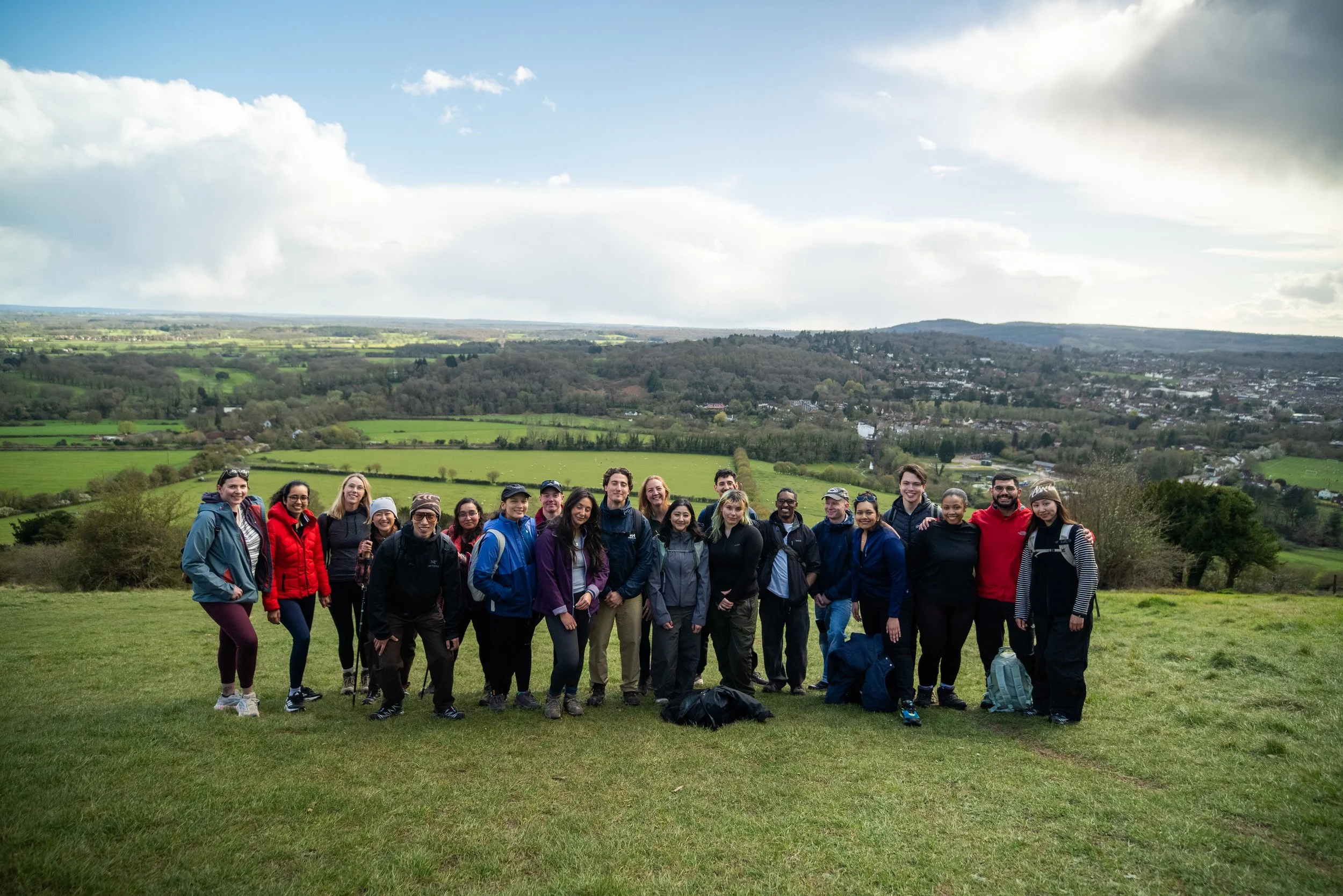 A peaceful river scene with stepping stones crossing the water, lush green foliage overhanging, and a moss-covered tree trunk on the right, reflecting in the river.