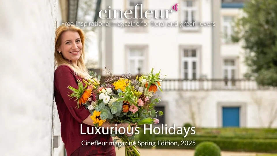 A woman holding a large bouquet of colorful flowers outdoors with a building in the background, on the cover of Cinefleur magazine's Spring Edition 2025.