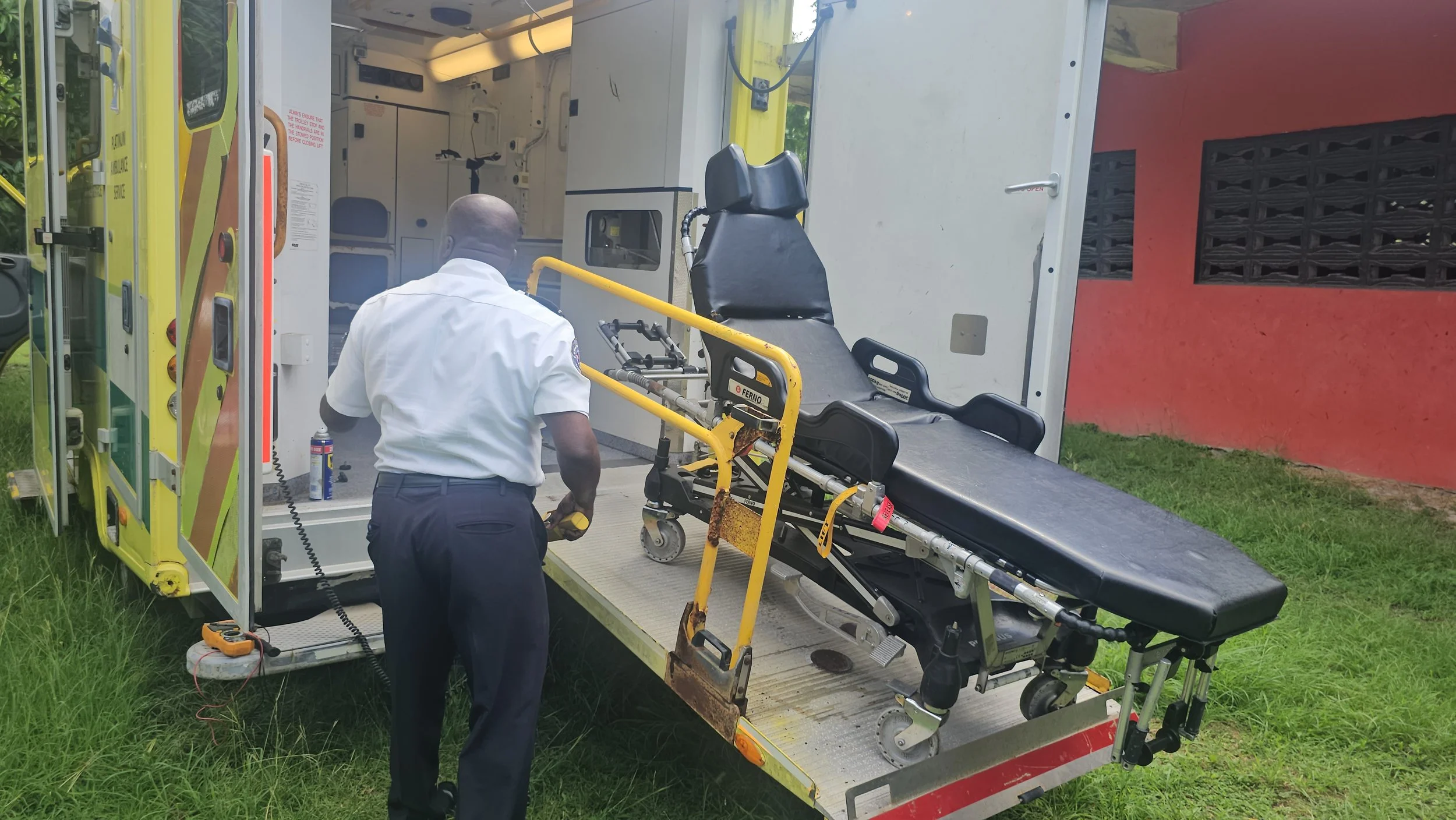 A paramedic is preparing a stretcher inside an ambulance for patient transport.