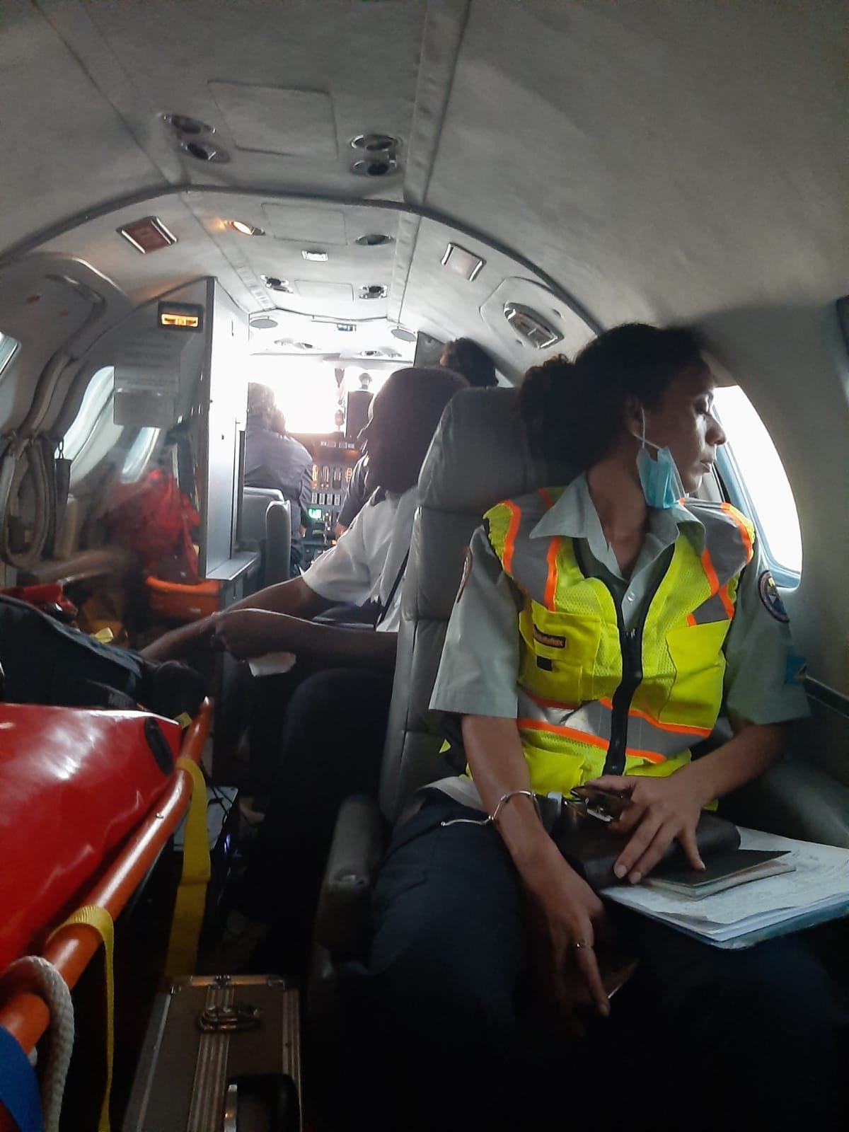 Inside a commercial airplane cockpit with crew members and passengers seated.