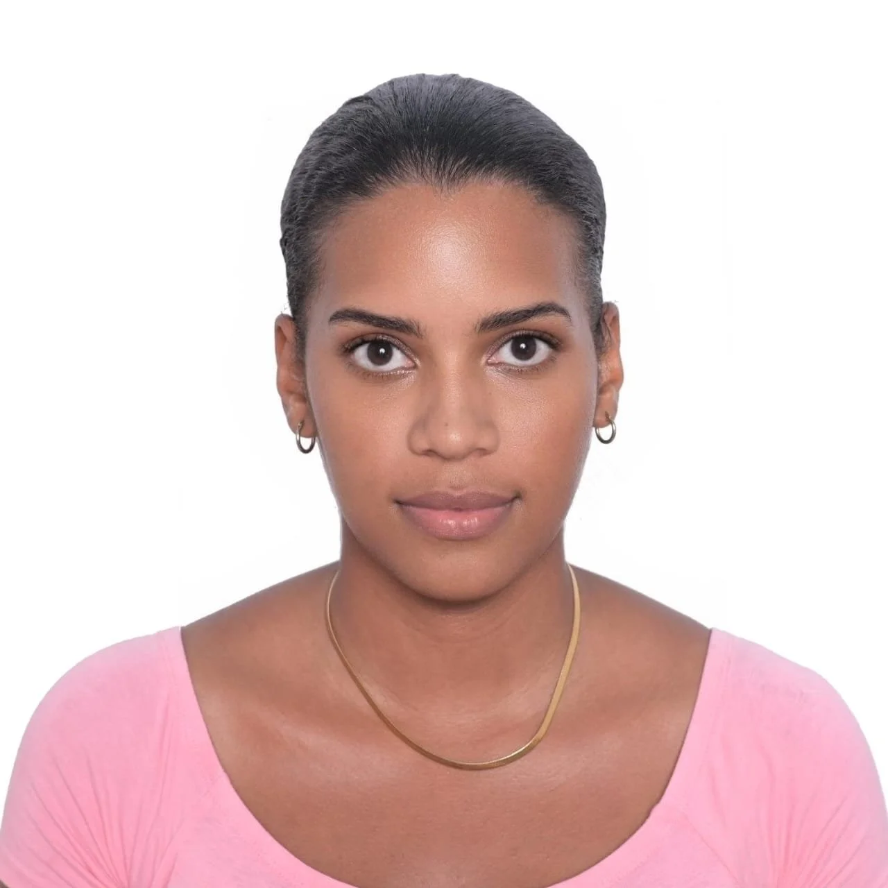 Portrait of a woman with dark hair, wearing a pink top and gold jewelry, against a white background.
