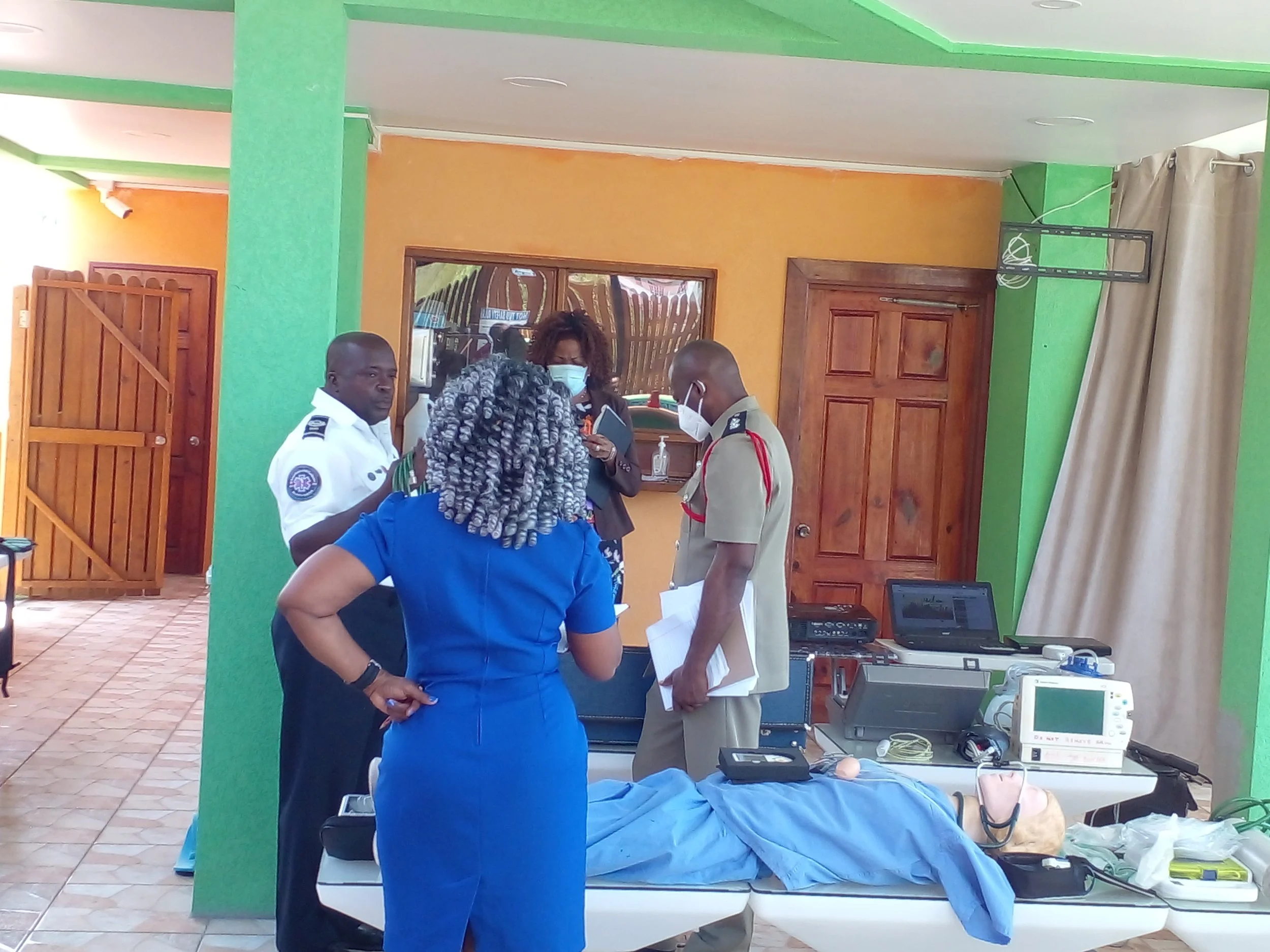 Medical professionals in a hospital room standing around a patient lying on a bed, with medical equipment and monitors nearby.